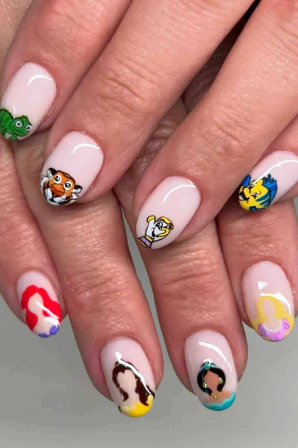Close-up of fingernails with colorful cartoon character nail art, including animals and princesses, on a light pink base.