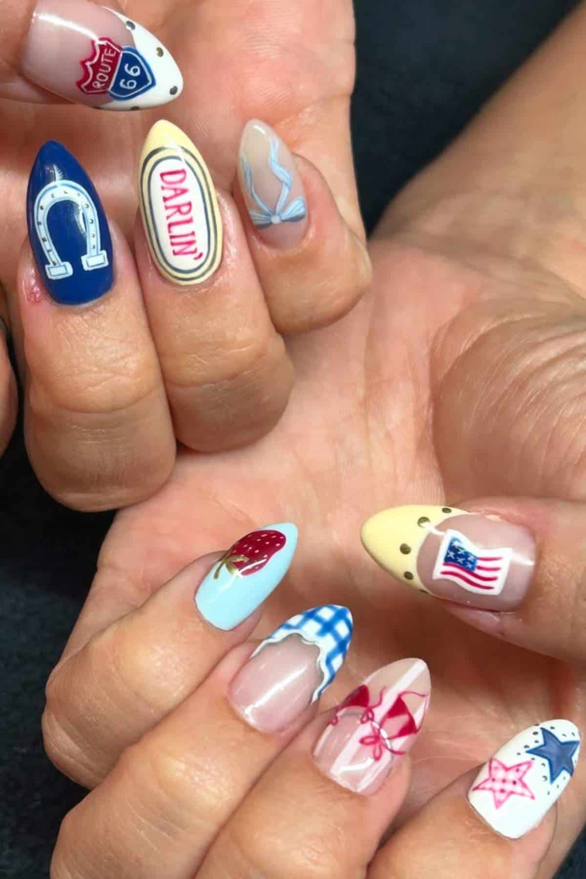 Close-up of hands with long, almond-shaped nails featuring colorful designs inspired by Route 66, cowboy hats, horseshoes, strawberries, and the American flag.