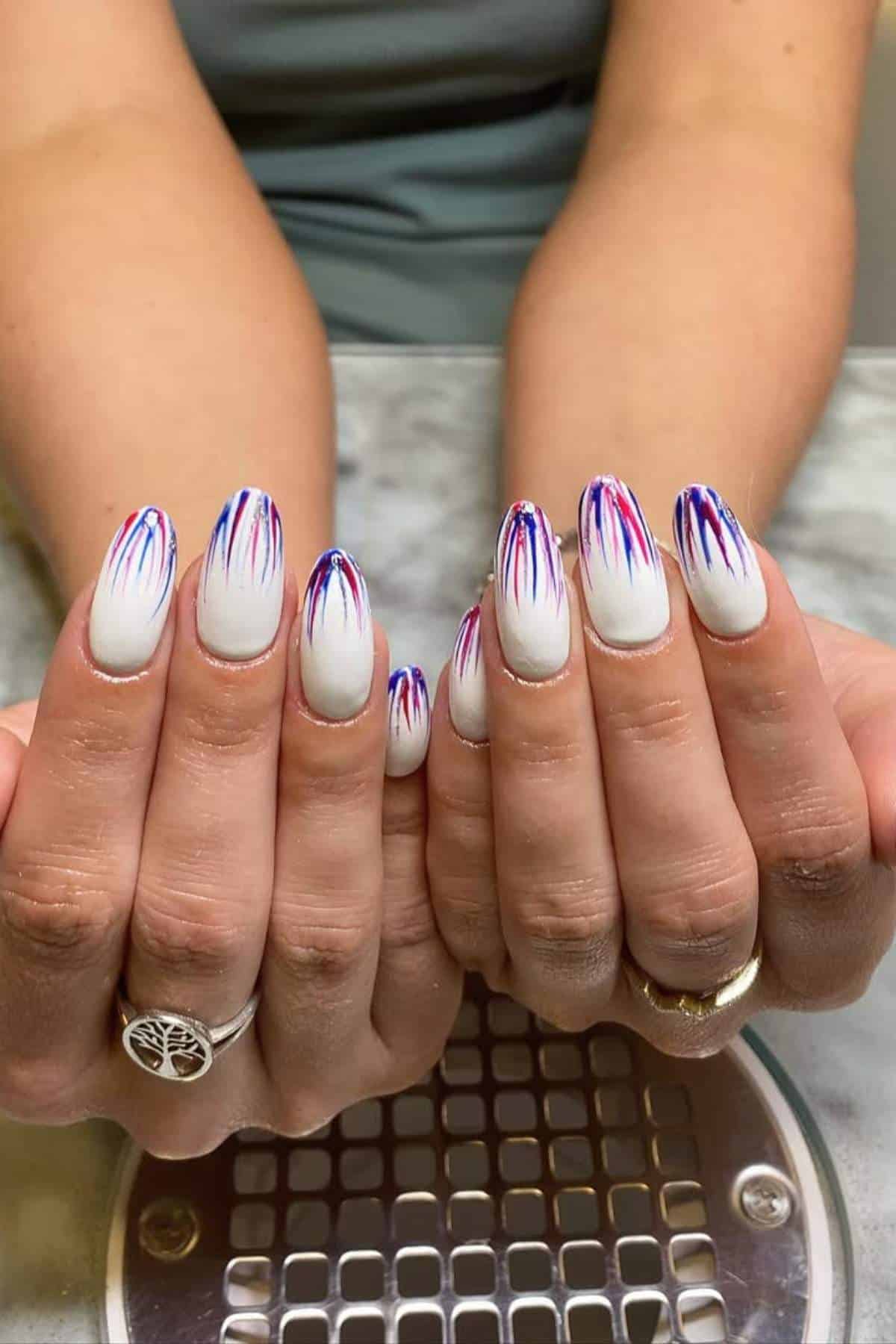 White oval nails with red, blue, and silver abstract stripes.