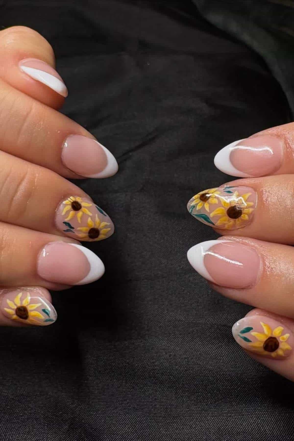 Hands with manicured nails; some nails have white French tips, while others feature painted sunflower designs on a neutral background.