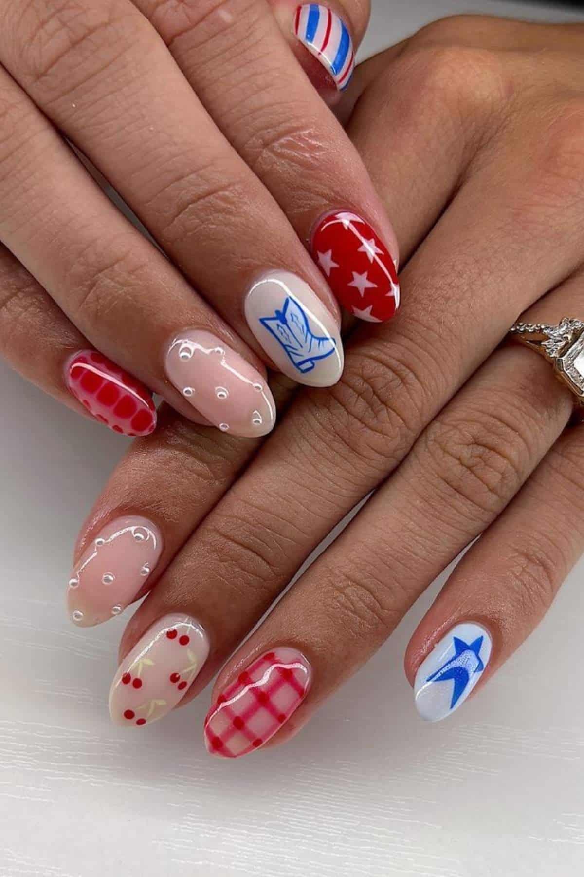 Hands with manicured nails featuring various red, white, and blue designs, including stars, stripes, hearts, dots, and checkered patterns.