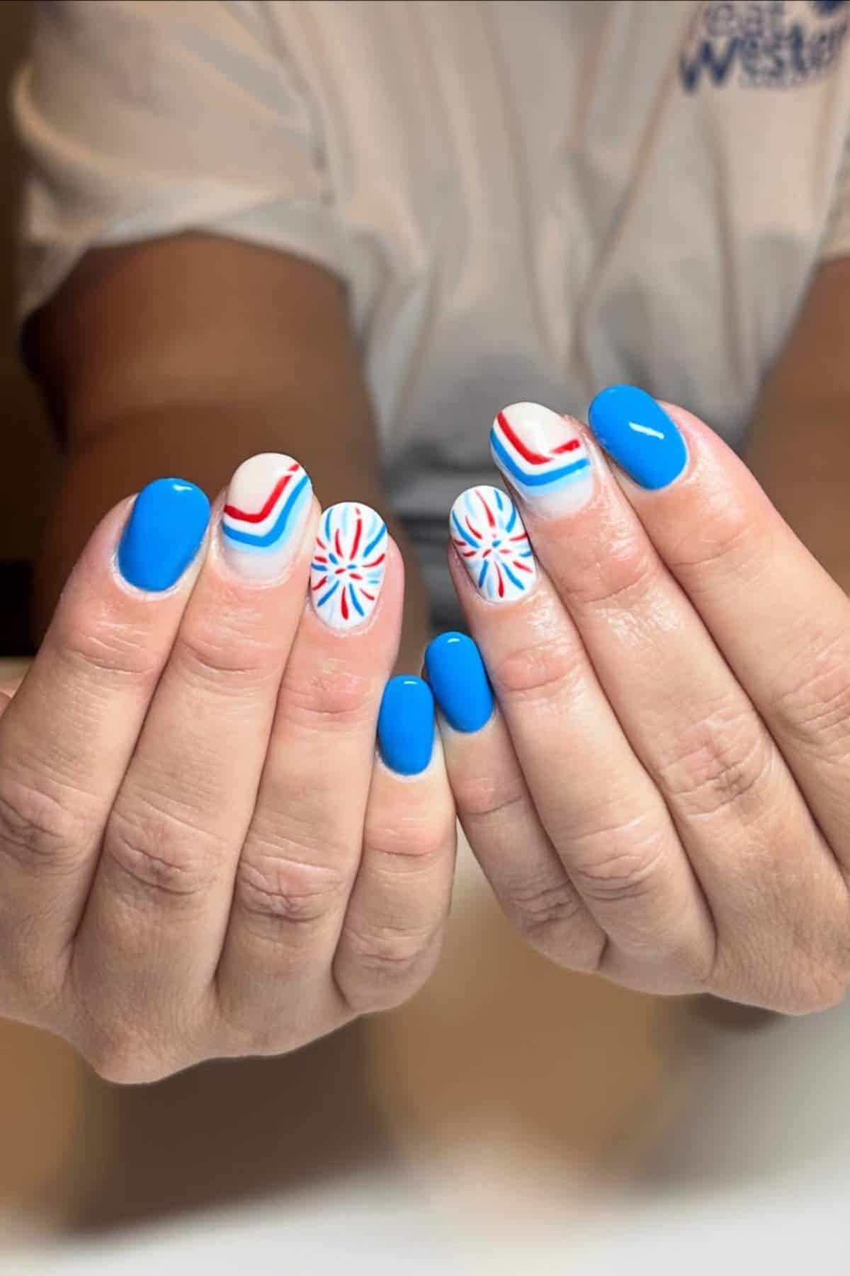 Hands with blue, white, and red patriotic-themed nails.