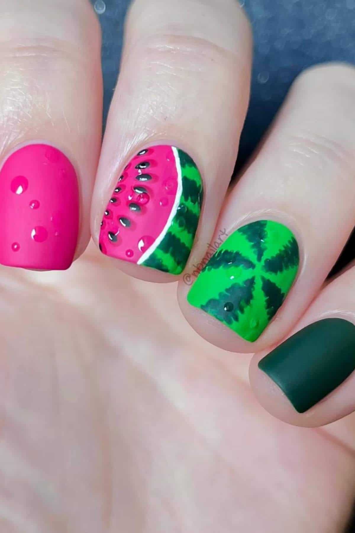Close-up of fingernails painted with watermelon-themed nail art, featuring pink, green, and black designs resembling watermelon slices and rind.