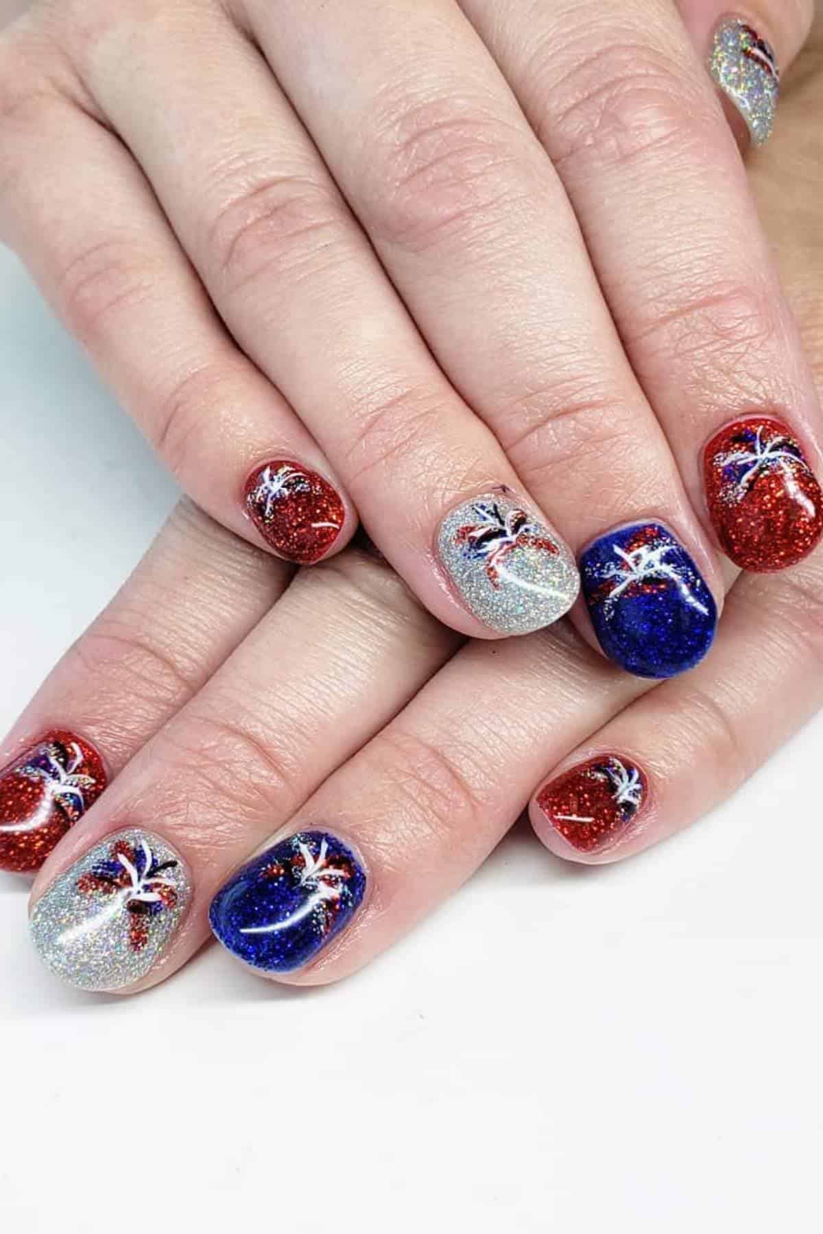 Glittery red, white, and blue nails with a starburst design.