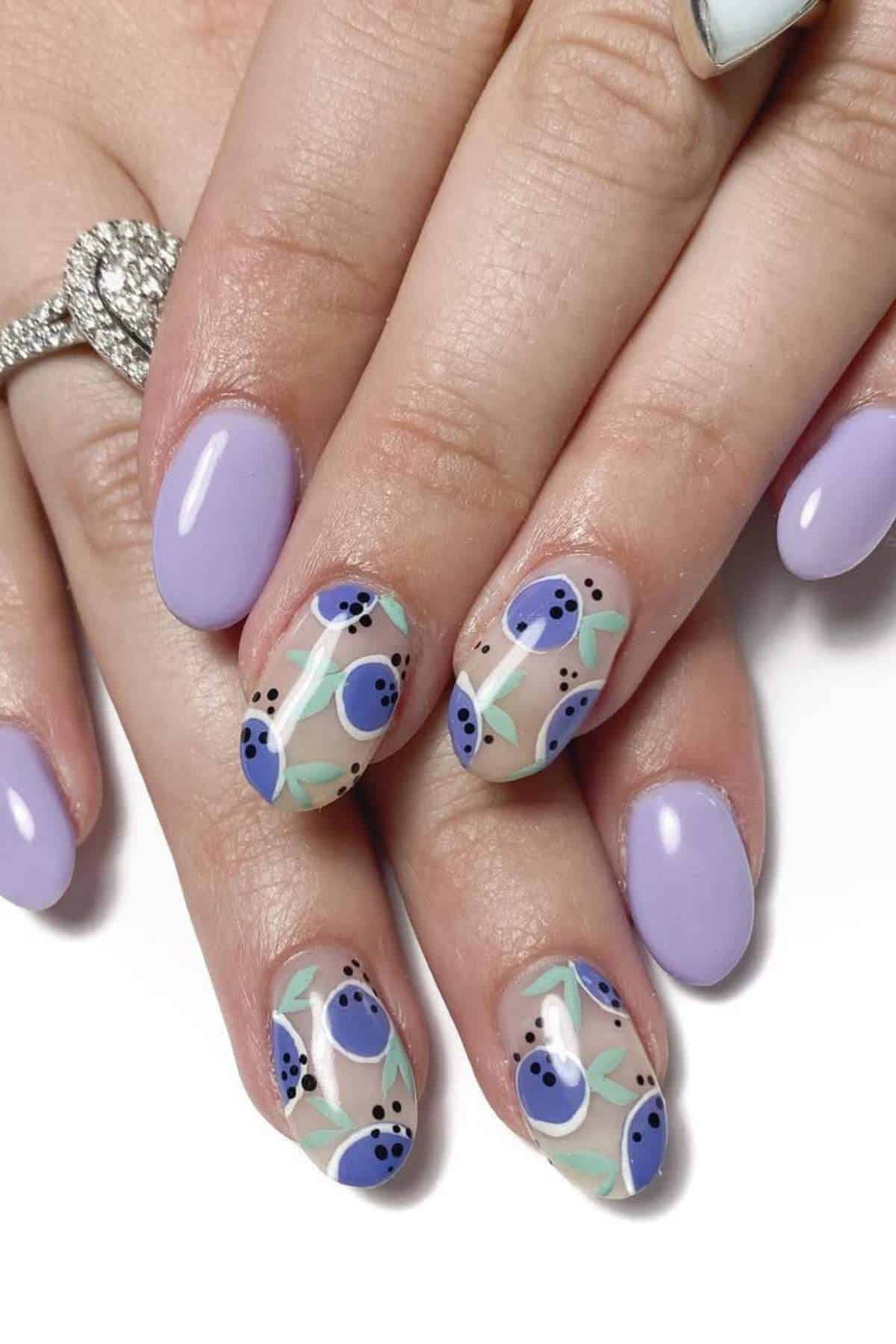Hands with lavender-colored nails; two nails on each hand feature a design with blue and purple floral patterns and green leaves.