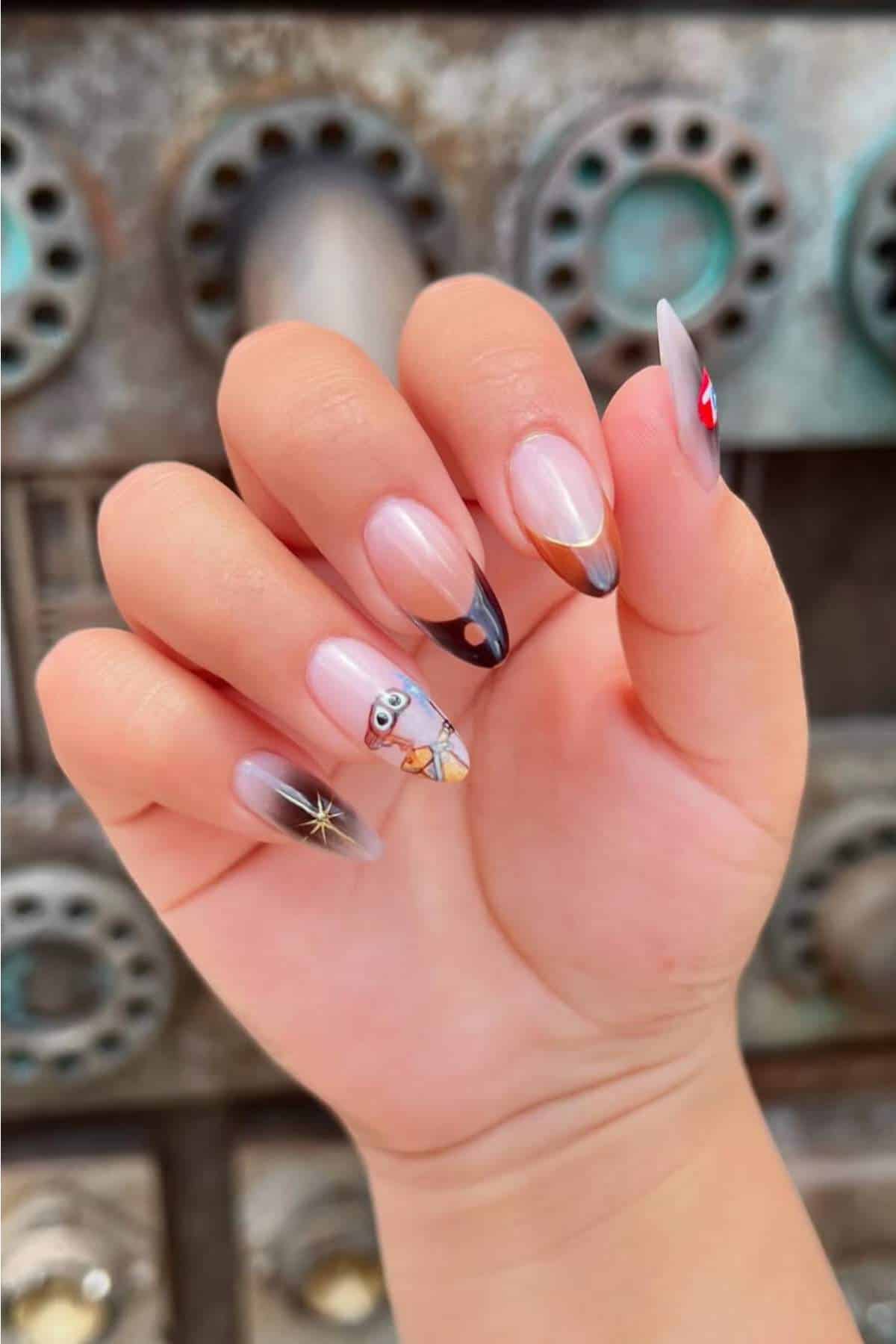 A hand with long, almond-shaped nails featuring black French tips, a star design, and a Minion character accent nail, against an industrial-style metal background.