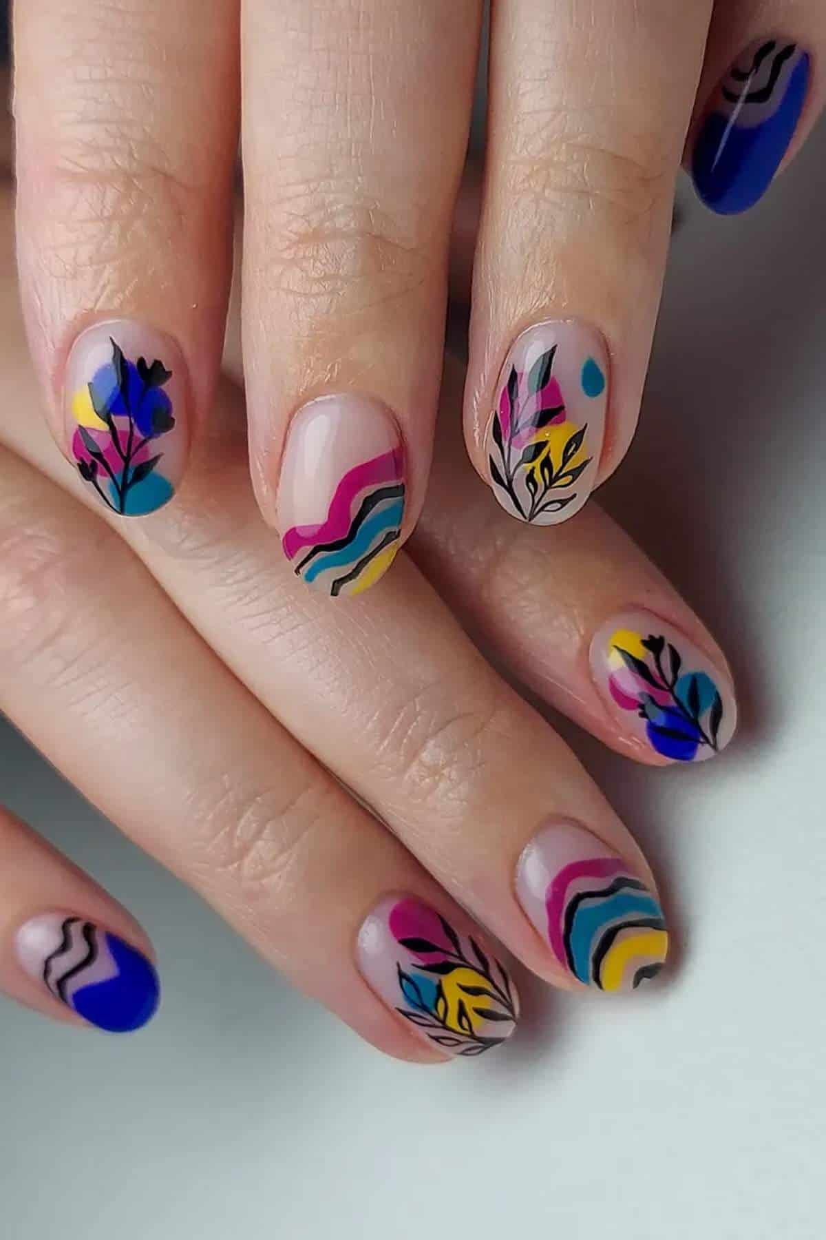 Hands with oval-shaped nails featuring colorful abstract and botanical designs, including wavy lines, leaves, and geometric shapes in blue, pink, yellow, and black.