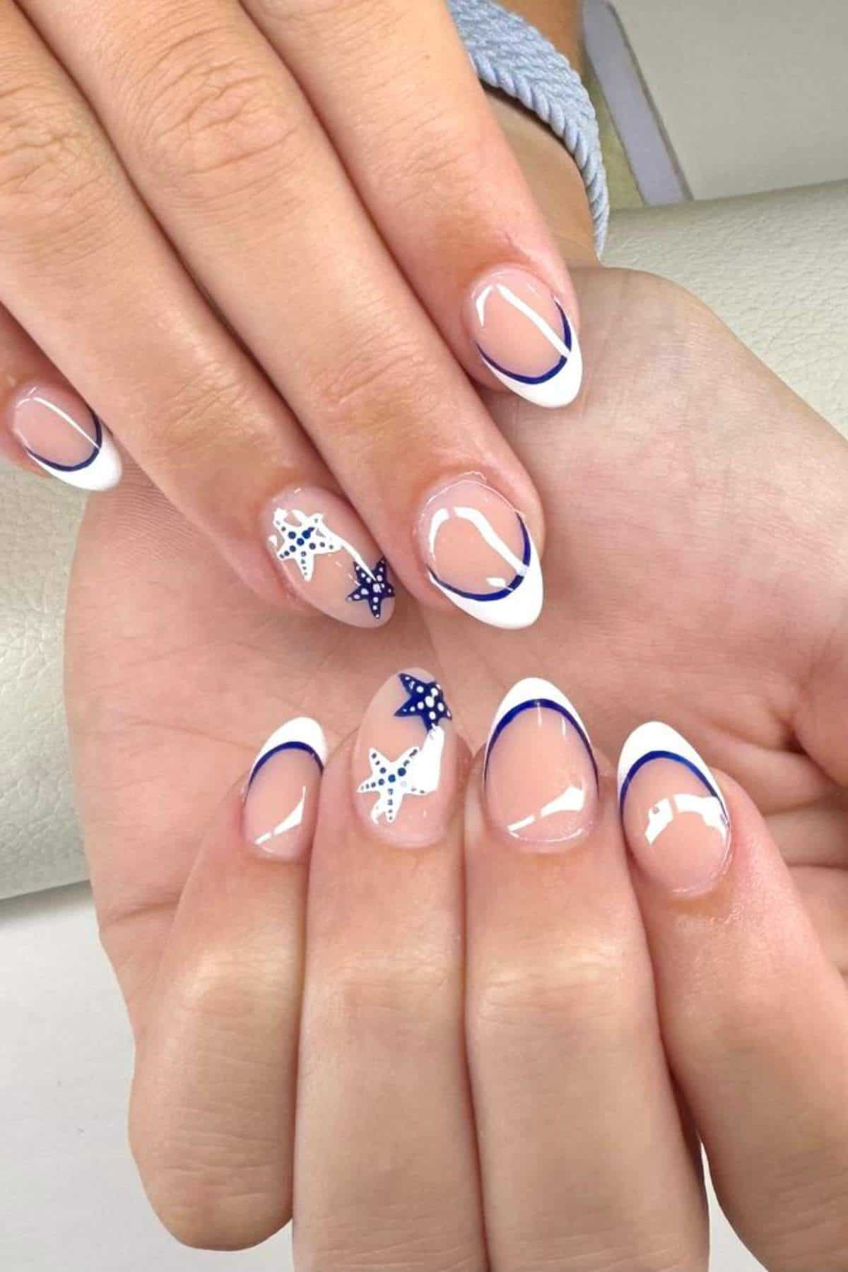 Hands with almond-shaped nails featuring a French manicure with white and blue tips and accent nails decorated with starfish and dots.