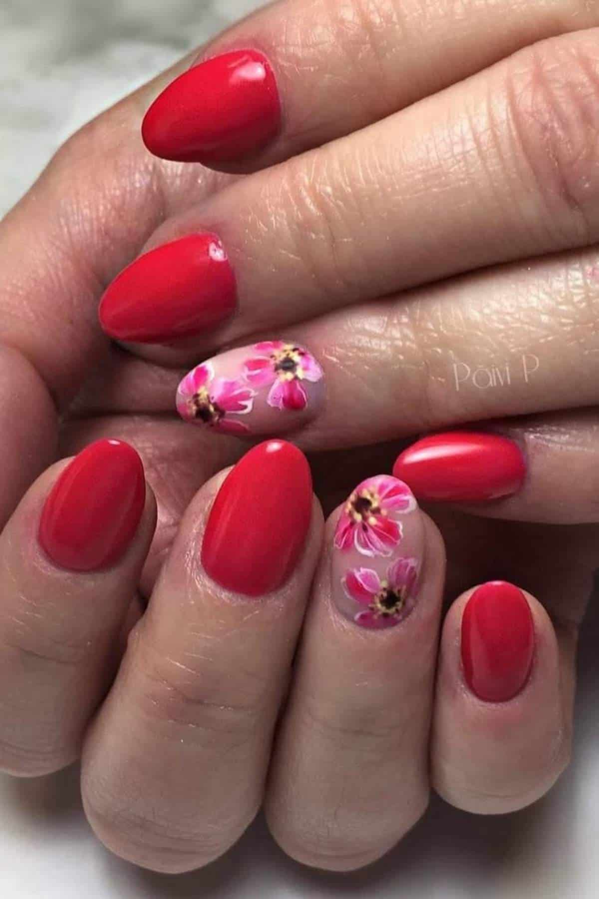 Hands with red polished nails; ring fingernails feature pink and yellow floral designs on a neutral base.