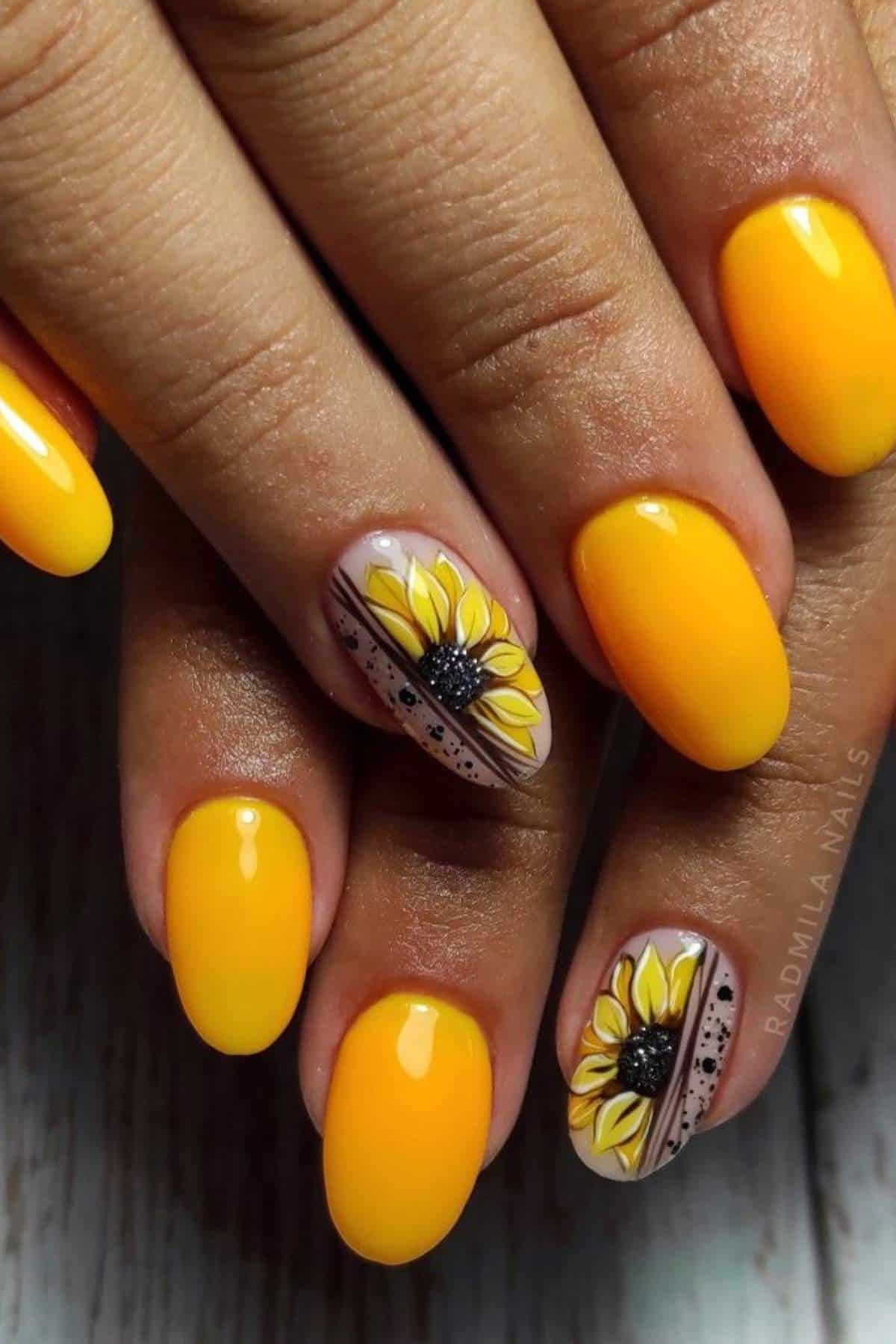 Close-up of hands with oval yellow nails; two accent nails feature detailed sunflower designs with black dots and stripes.