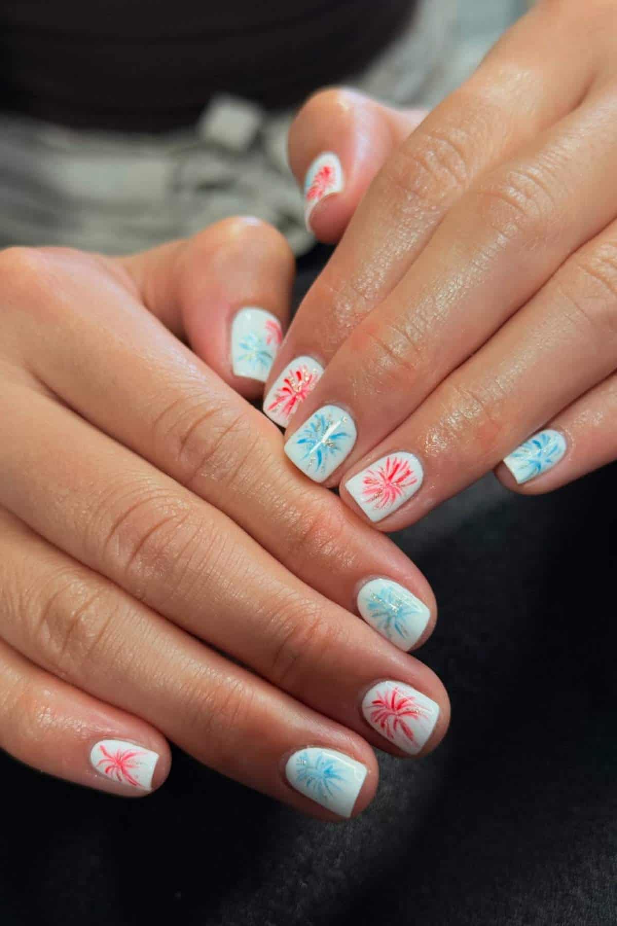 White nails with red and blue firework designs.