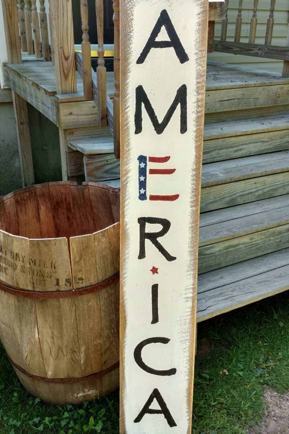 A vertical wooden sign with "AMERICA" painted in black letters and an American flag detail.