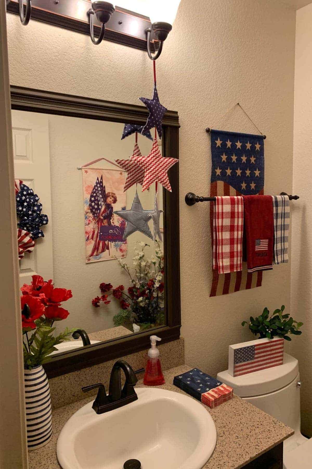 A bathroom decorated with American patriotic-themed items, including stars, flags, and red, white, and blue towels and flowers.