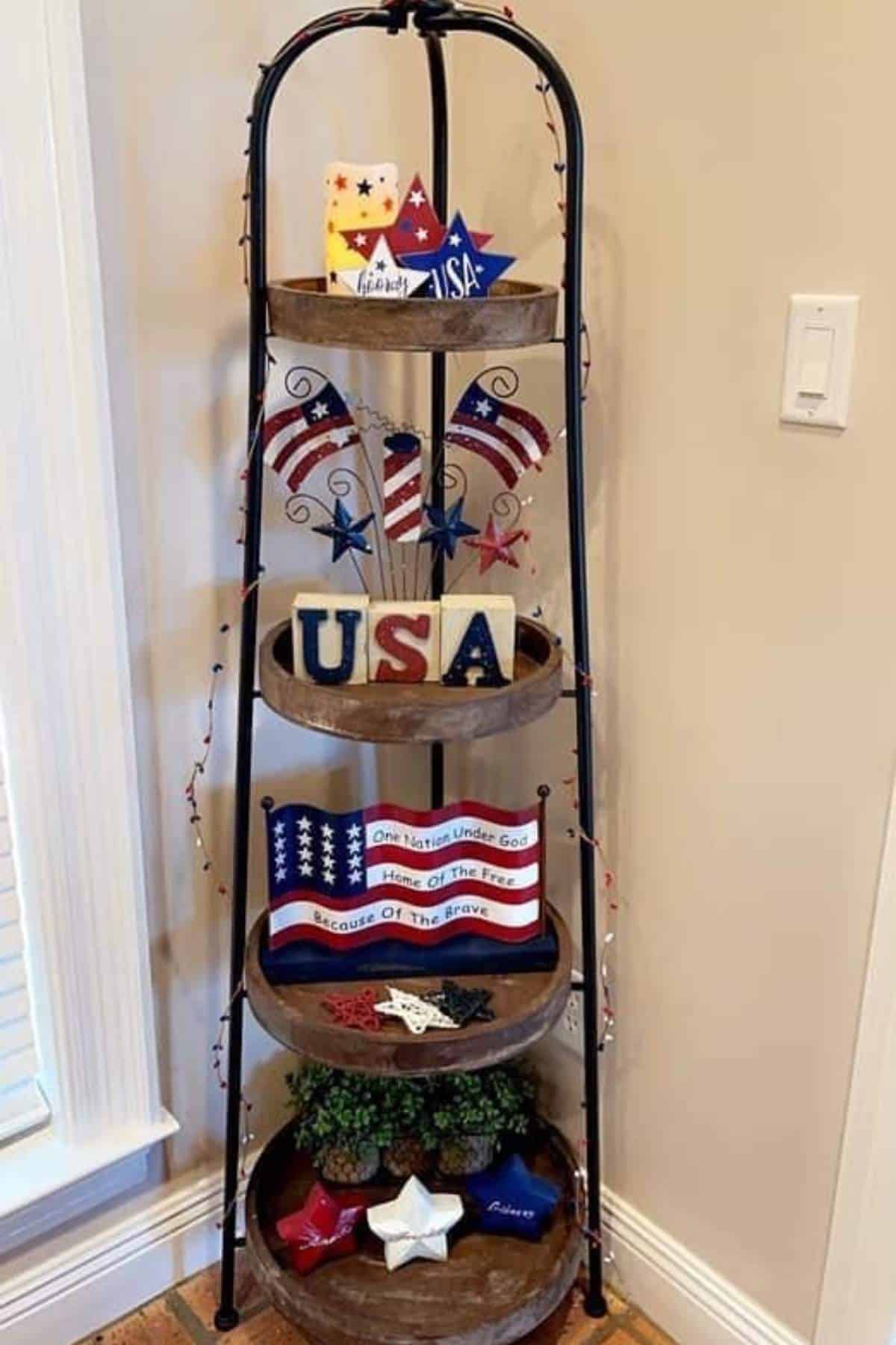 A four-tiered corner shelf decorated with patriotic USA-themed ornaments, including stars, flags, and signs in red, white, and blue colors.