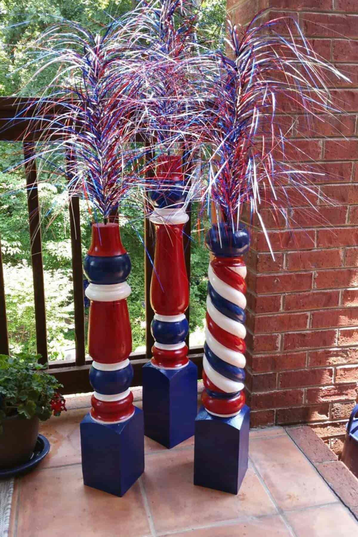 Three patriotic decorations with red, white, and blue streamers stand on a tiled porch.