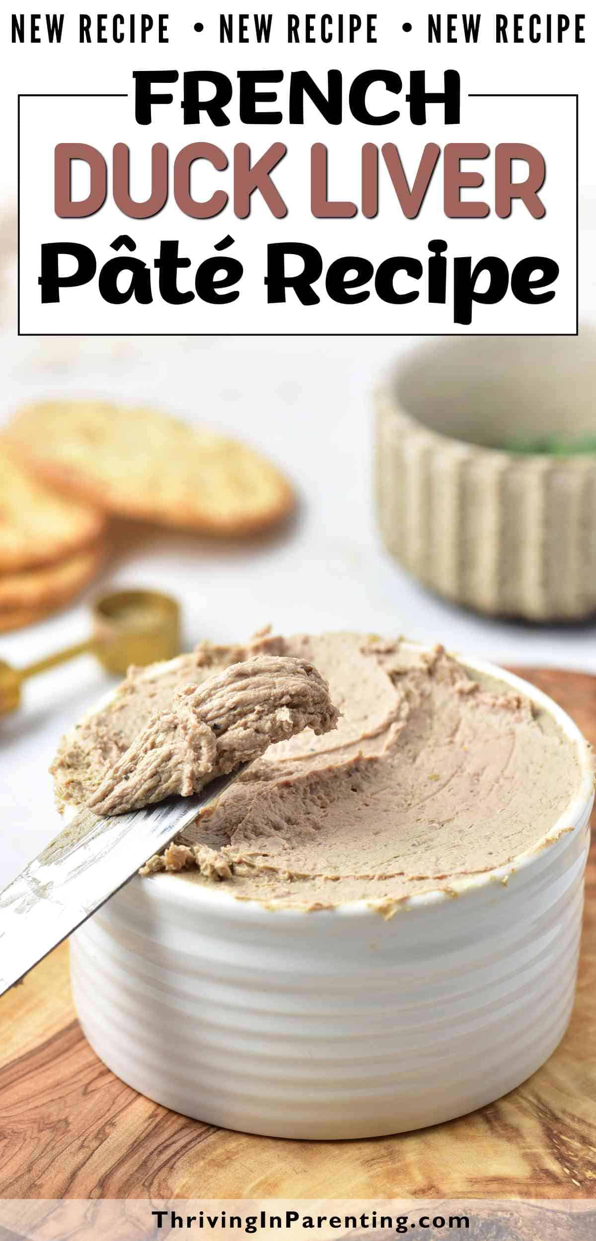 A white ramekin filled with duck liver pate, with a knife spreading the rich pâté on top; crackers and a mug are in the background.