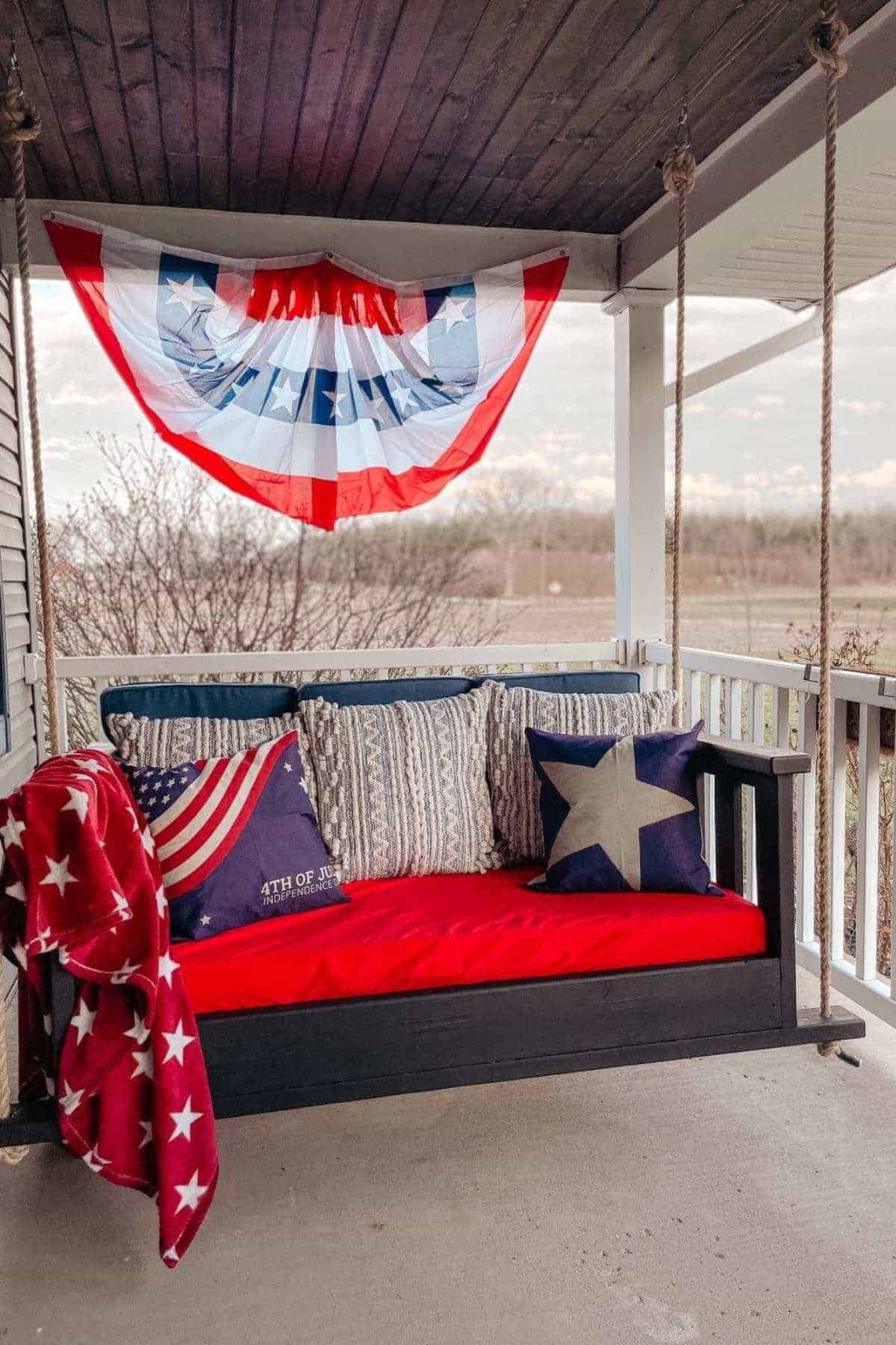 A porch swing decorated with patriotic pillows and a star-spangled throw.