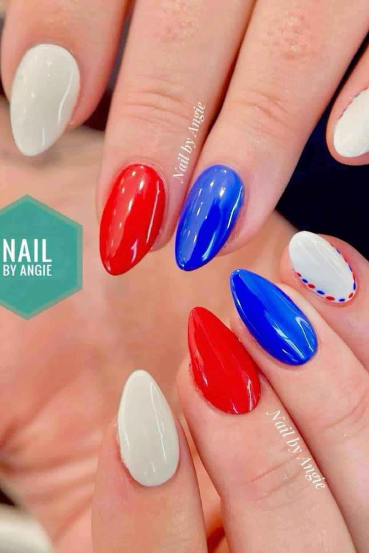 Close-up of hands with almond-shaped nails painted in white, red, and blue polish, some with dotted nail art; "Nail by Angie" logo visible.