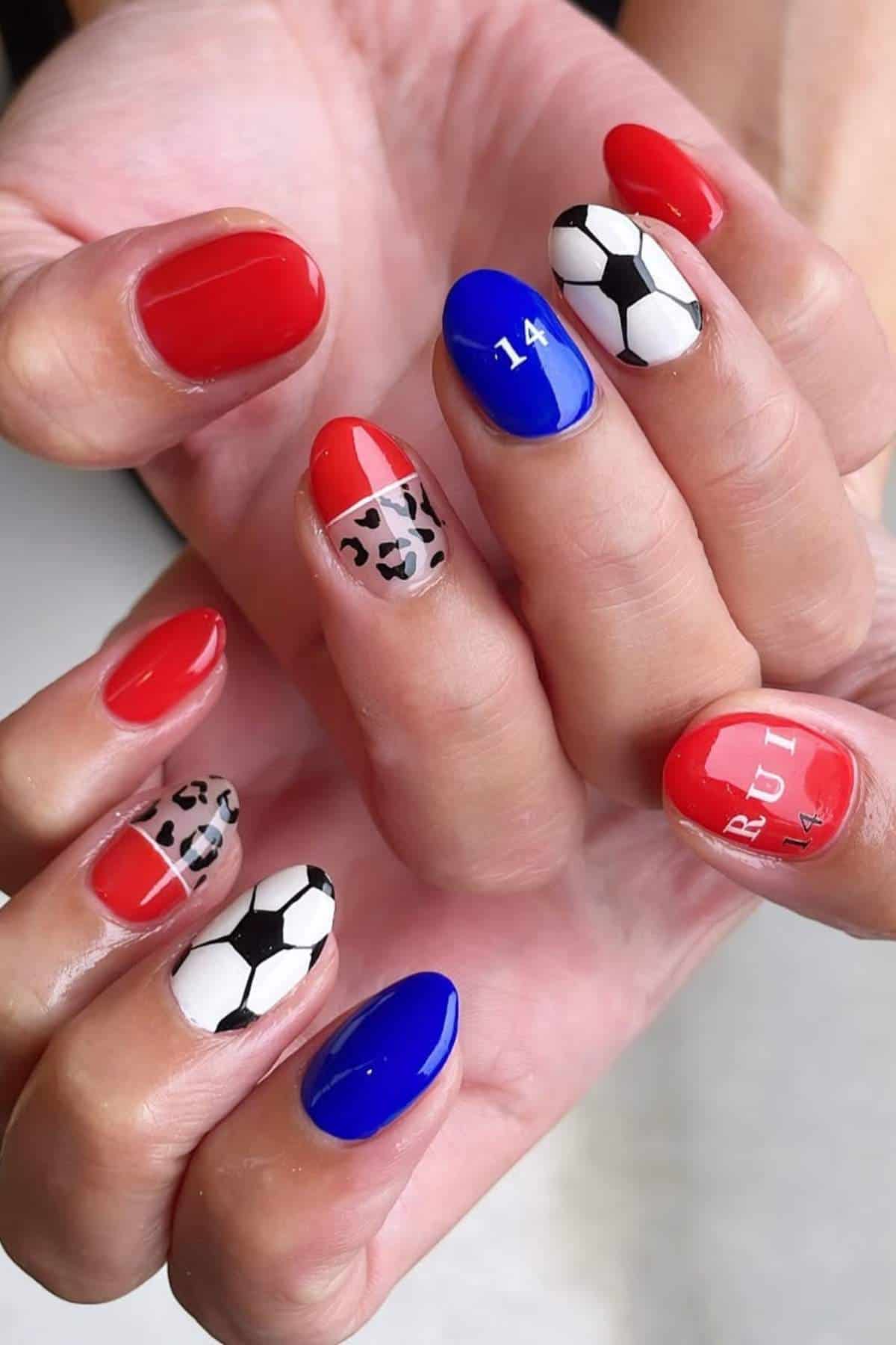 Hands with manicured nails featuring red, blue, leopard print, soccer ball designs, the number 14, and the name "RUI" on the ring and middle fingers.