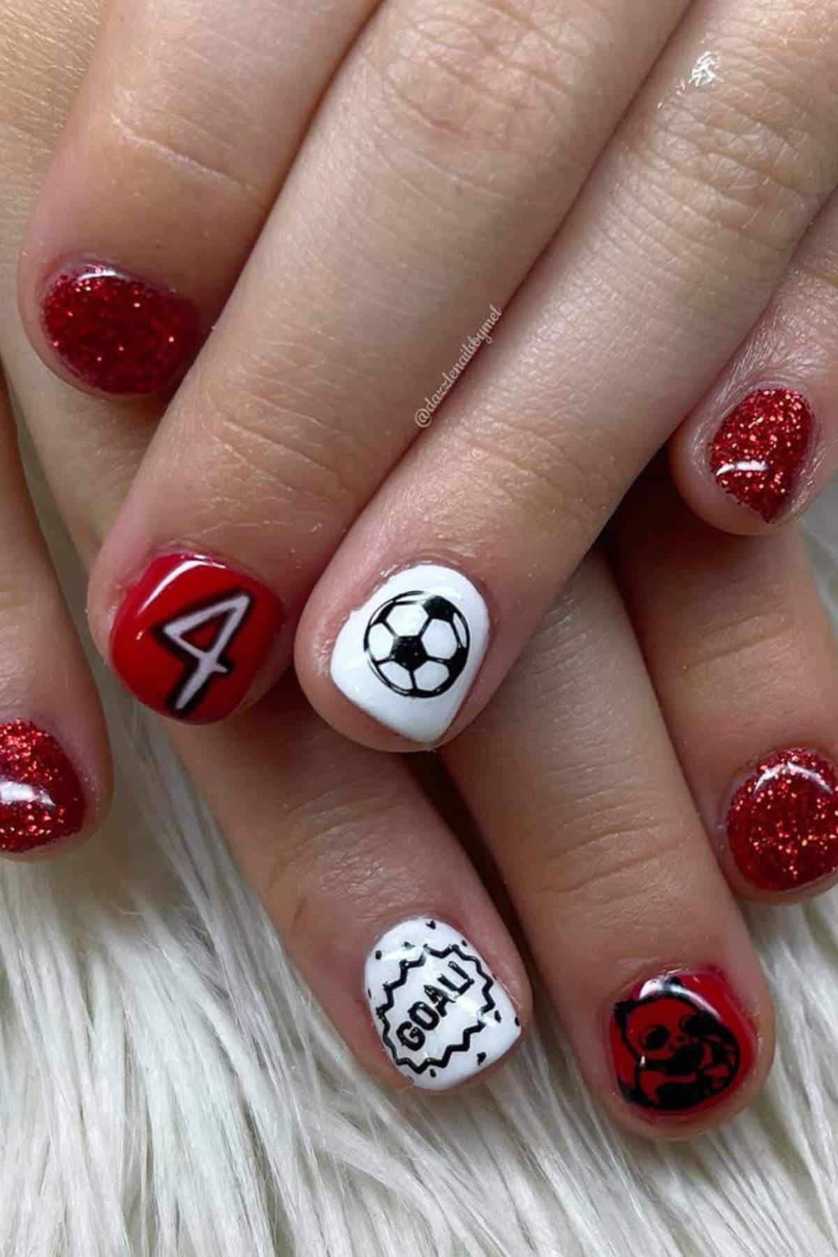 Fingernails painted with a soccer theme: red glitter polish, a number 4, a soccer ball, the word "GOAL!", and a black and red soccer ball design.