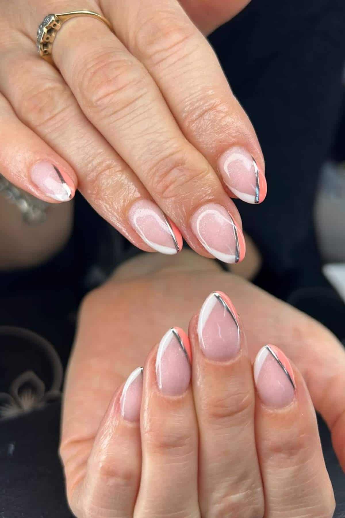 Close-up of hands with almond-shaped nails featuring pink, white, and black geometric nail art.