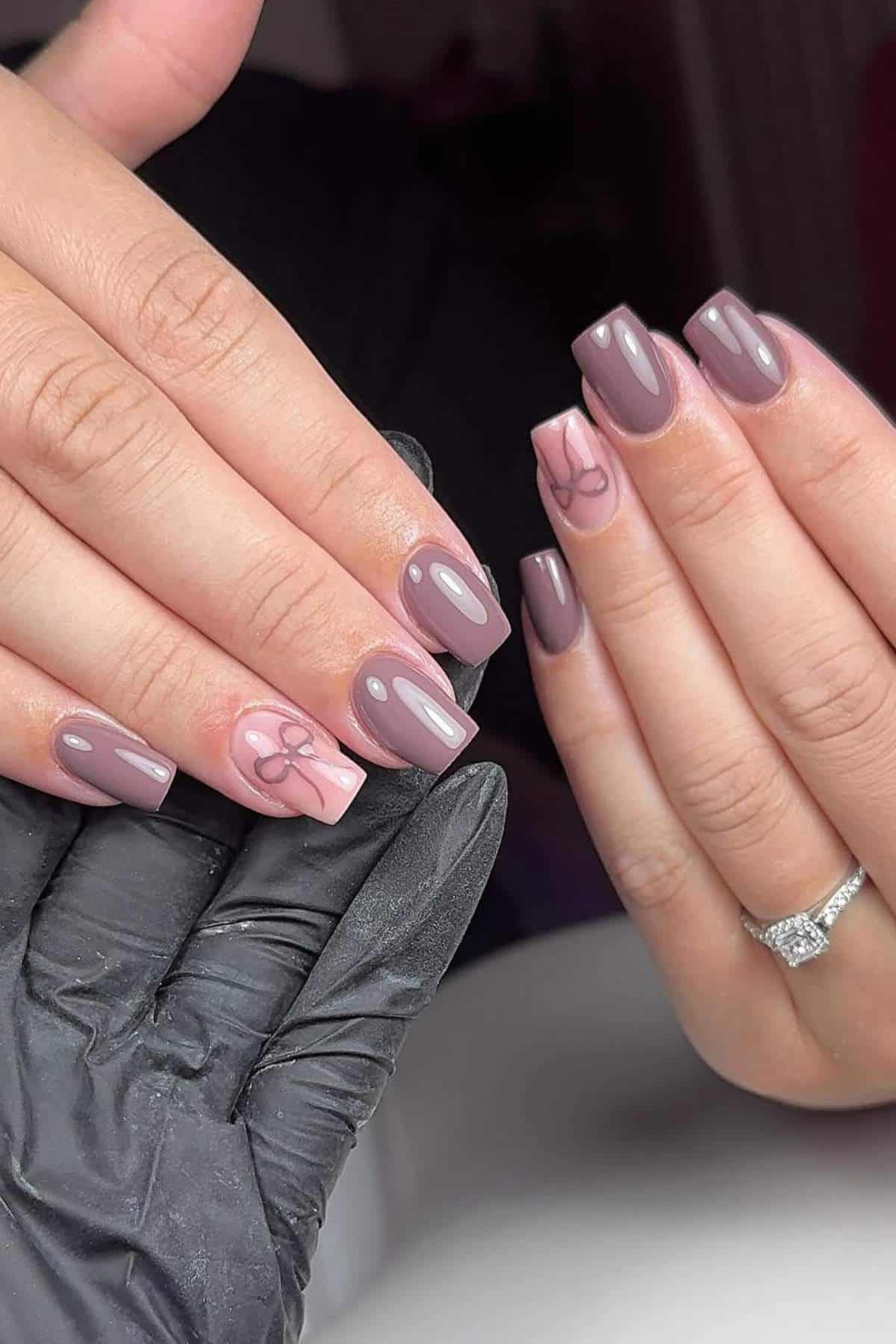 Hands with square-shaped, glossy mauve gel nails; ring finger features a pale accent nail with a minimal abstract line design. One hand wears a diamond ring; the other is gloved.