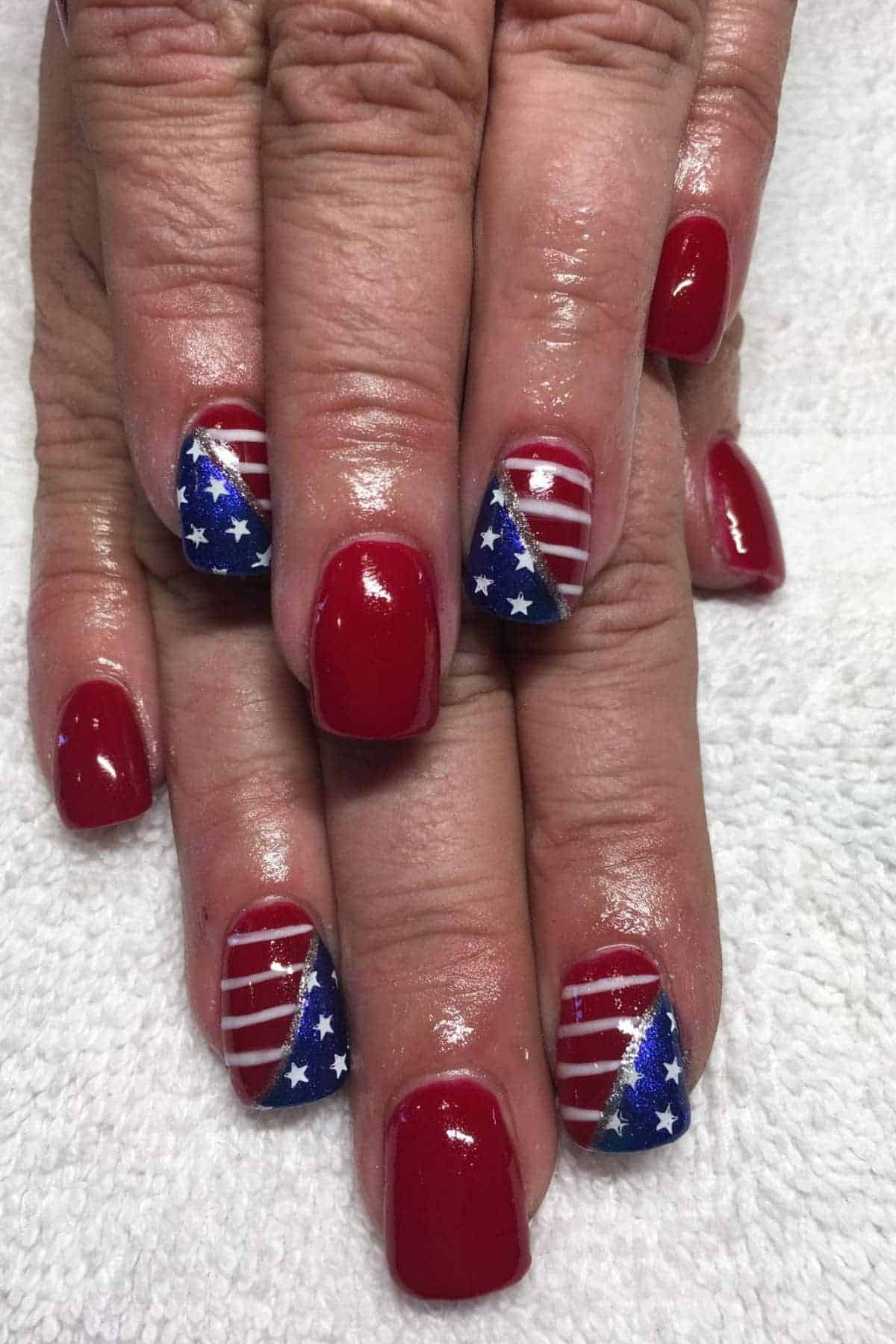 Hands with short, shiny red nail polish; ring fingernails feature a blue and white stars and stripes American flag design.