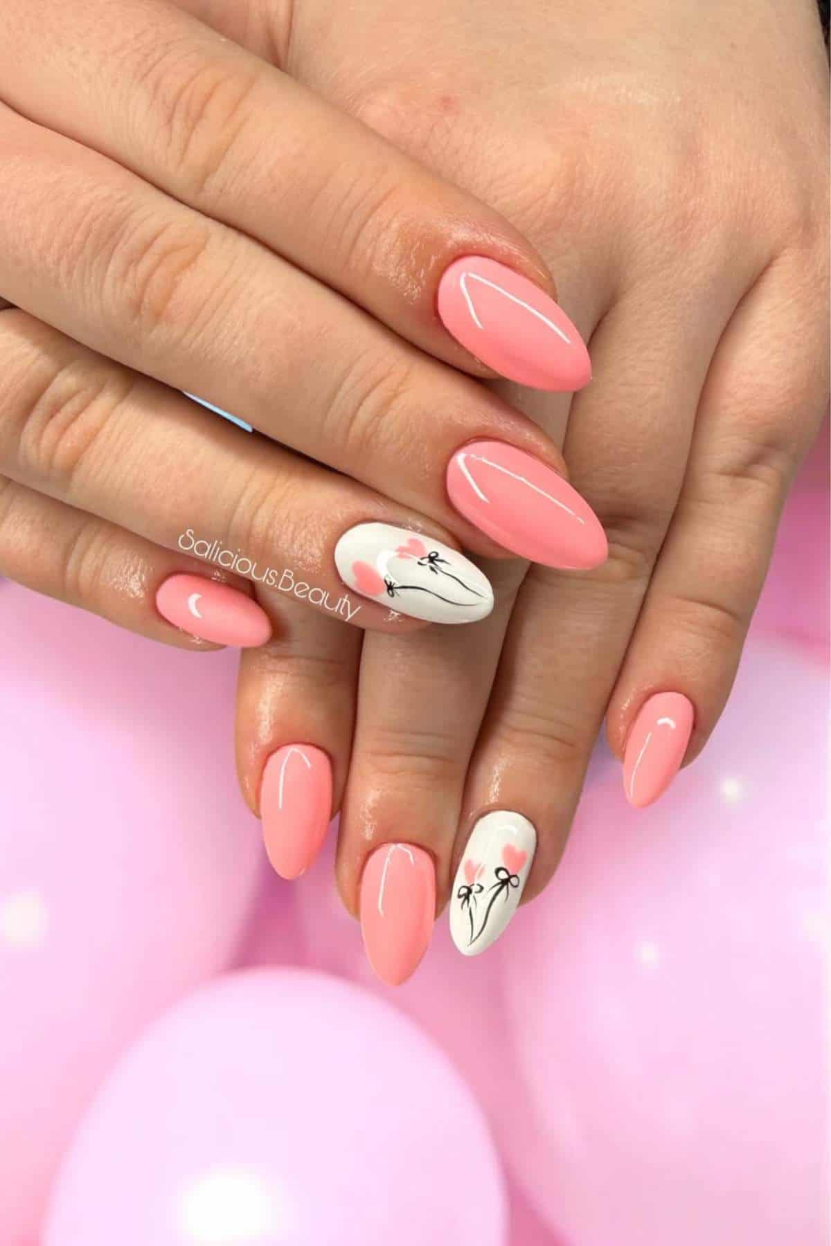 Hands with almond-shaped nails painted pink, featuring white accent nails with minimalist flower designs; pink balloons are in the background.