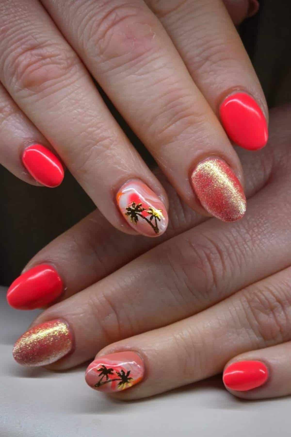 Hands with oval-shaped nails painted in bright coral, gold shimmer, and accent nails featuring black palm tree designs over a sunset background.