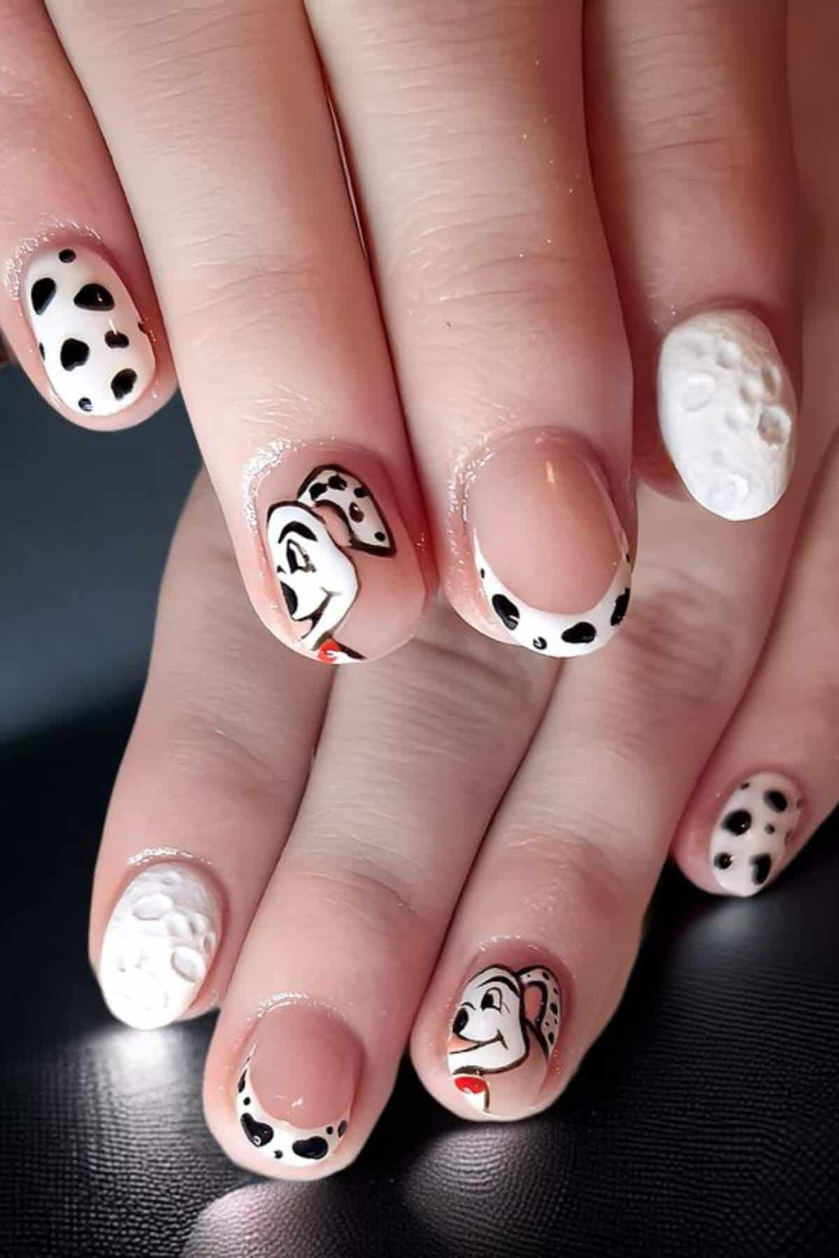 Hands with manicured nails featuring white polish, black spots, and cartoon dog faces resembling a Dalmatian theme.