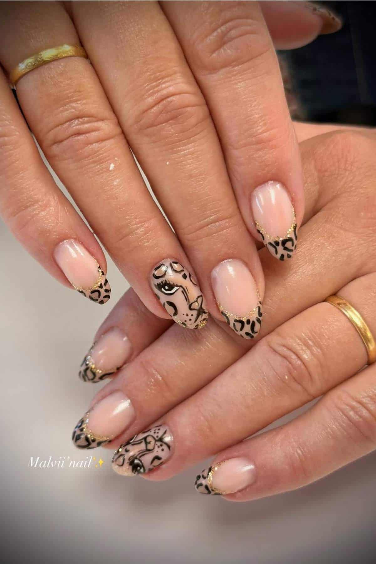Hands with nude and black animal print French tip nails, featuring an artistic eye and face design on the ring fingers.