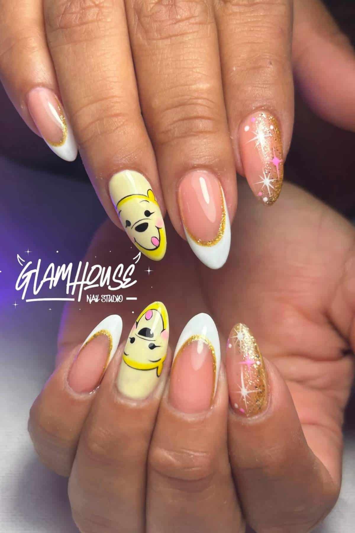 Close-up of hands with almond-shaped nails featuring gold glitter, white French tips, and cartoon face nail art on two fingers.