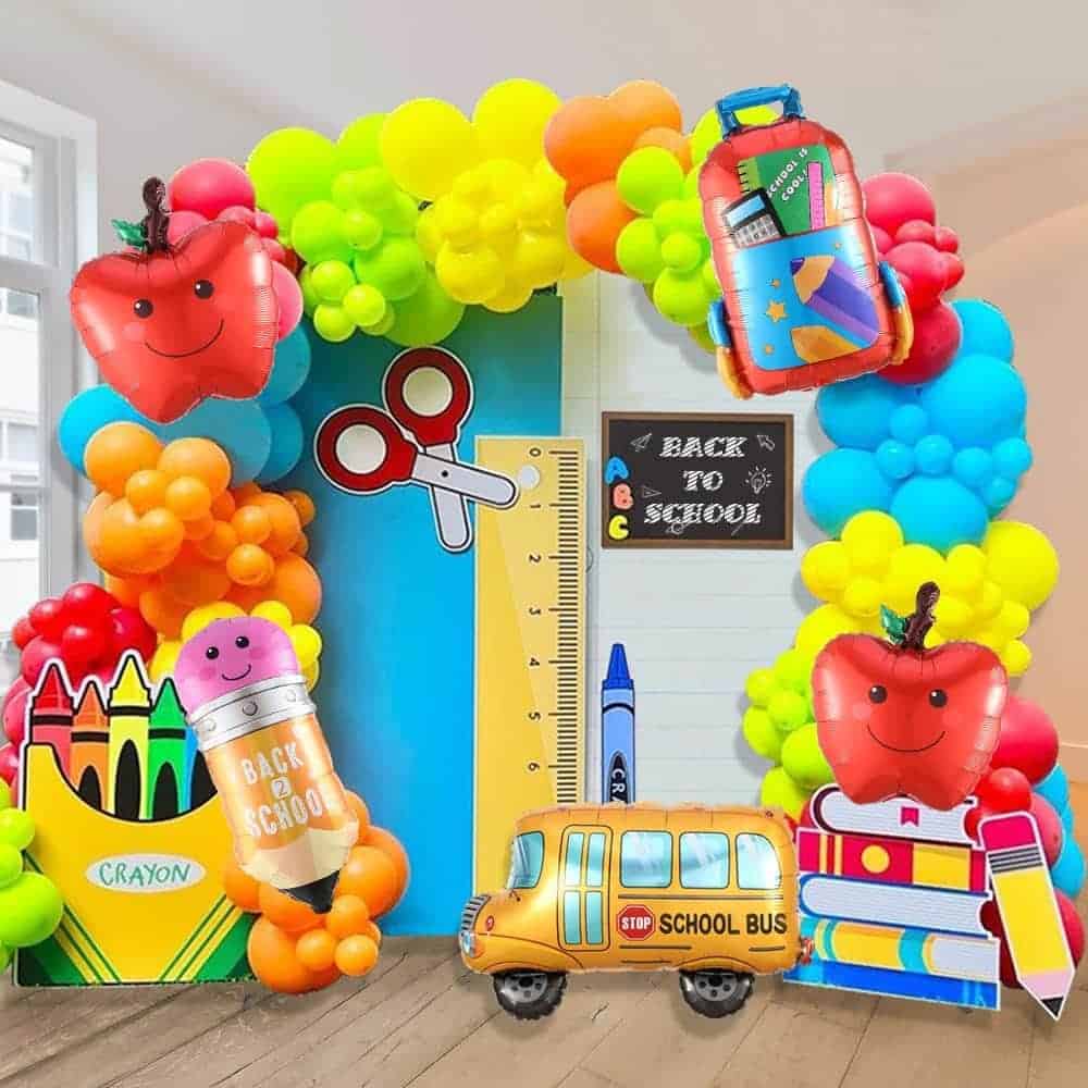 Colorful balloon arch with school-themed decorations, including apples, crayons, a pencil, a ruler, school bus, books, and a “Back to School” sign.