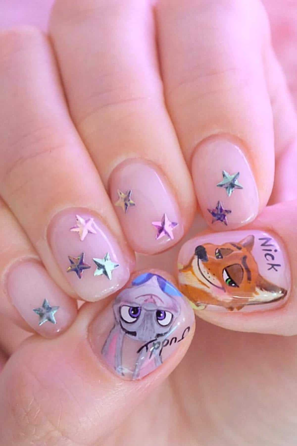 A hand with nude-colored nails featuring silver star decorations and detailed illustrations of Judy Hopps and Nick Wilde from Zootopia on the thumb and ring finger.