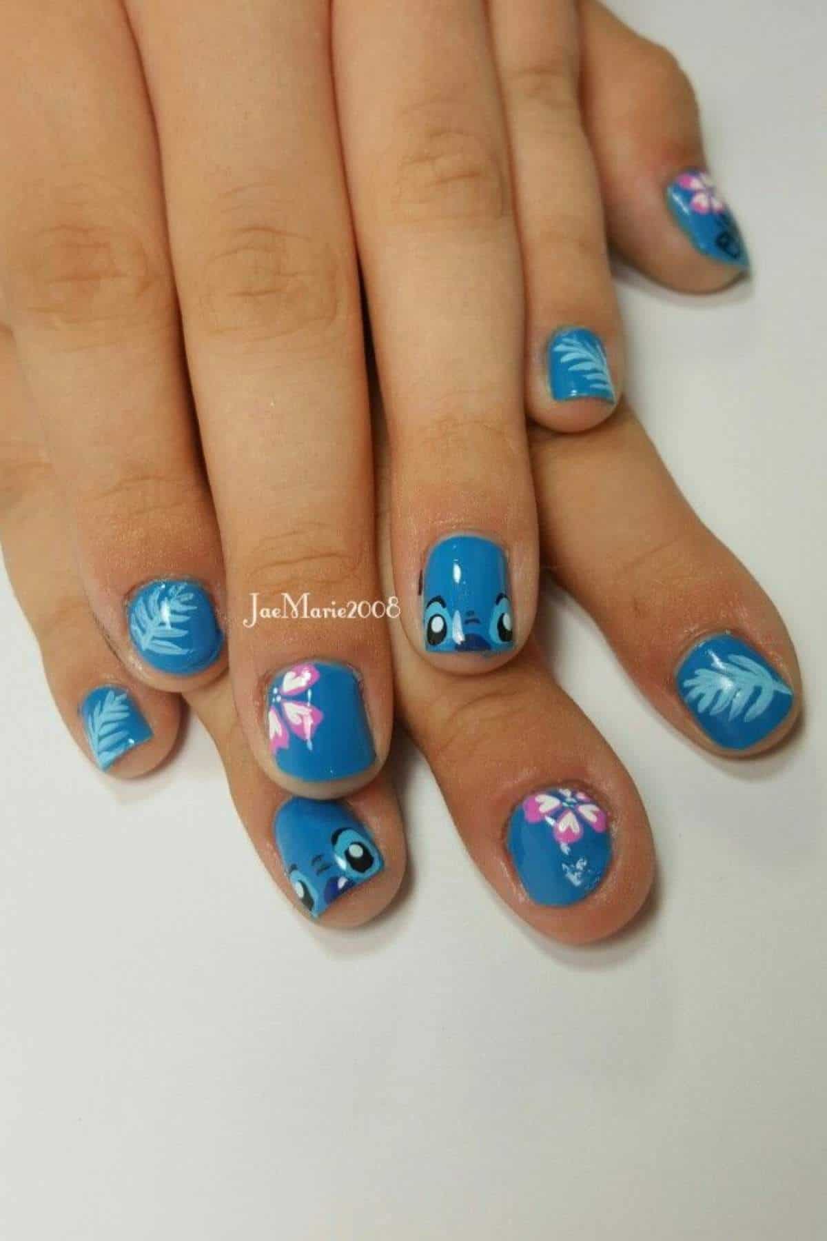 Hands with short nails painted blue, featuring cartoon eyes, white leaves, and pink bows as nail art designs.