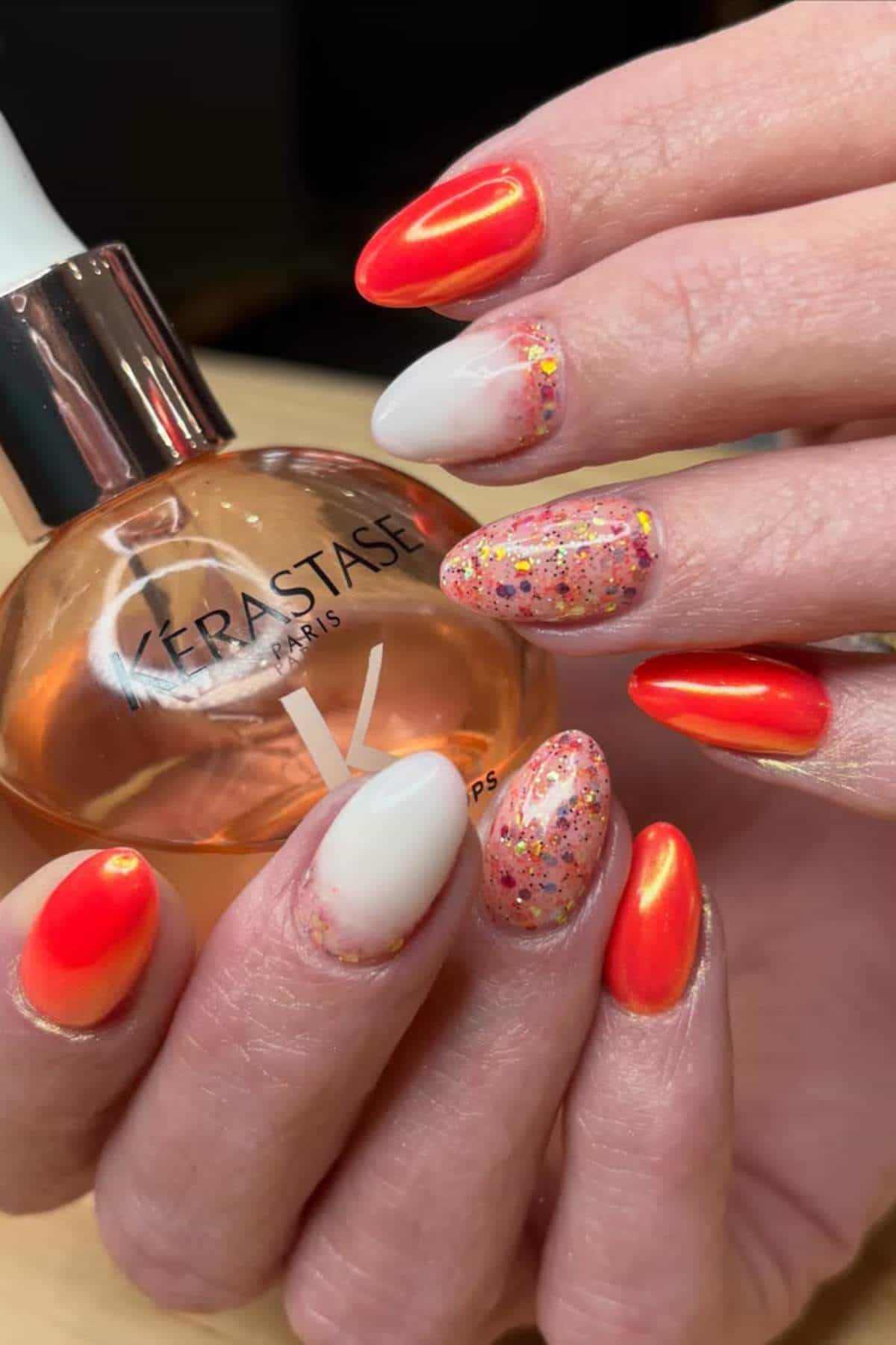 Colorful holiday-themed manicure with red, white, and glittery nails, showcasing festive nail art de.
