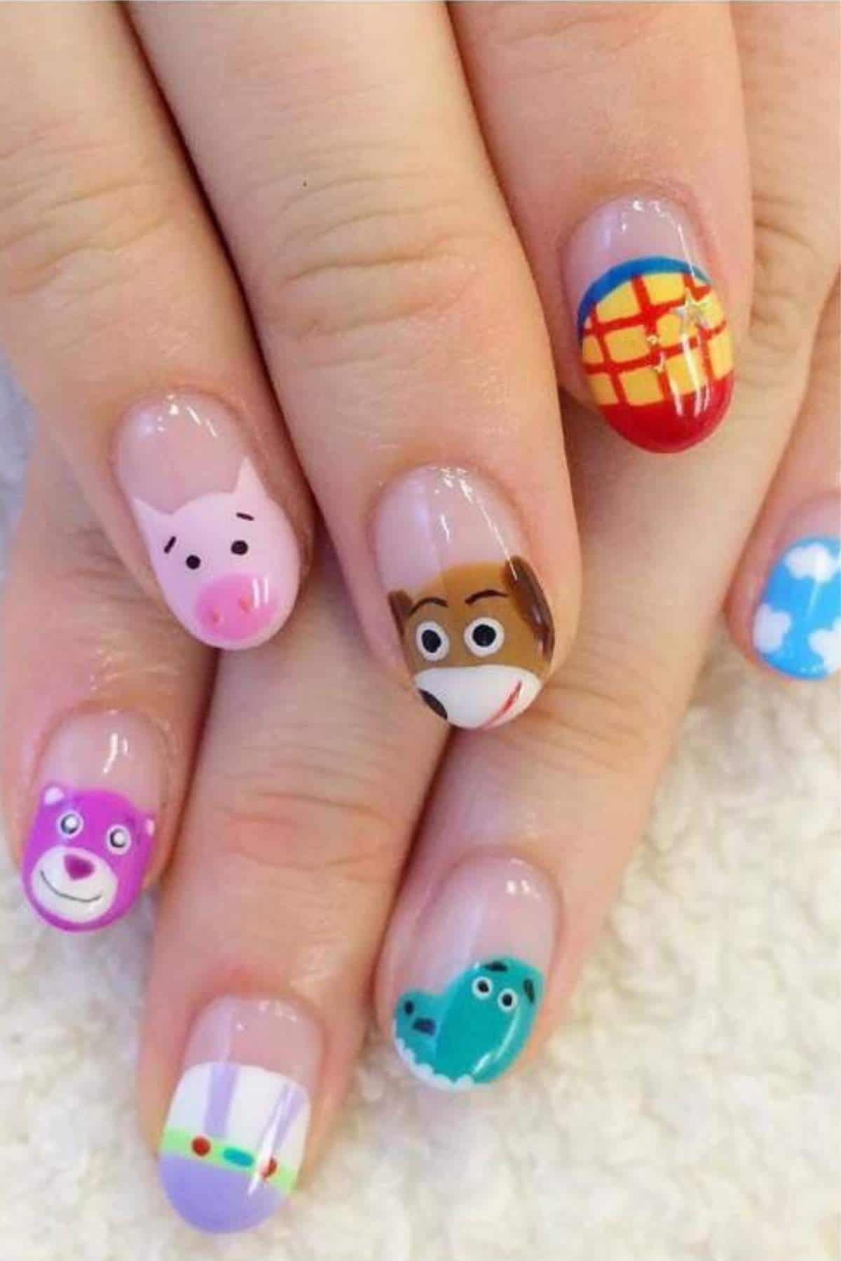 A hand with manicured nails painted with various Toy Story character designs and themed patterns on each fingernail.
