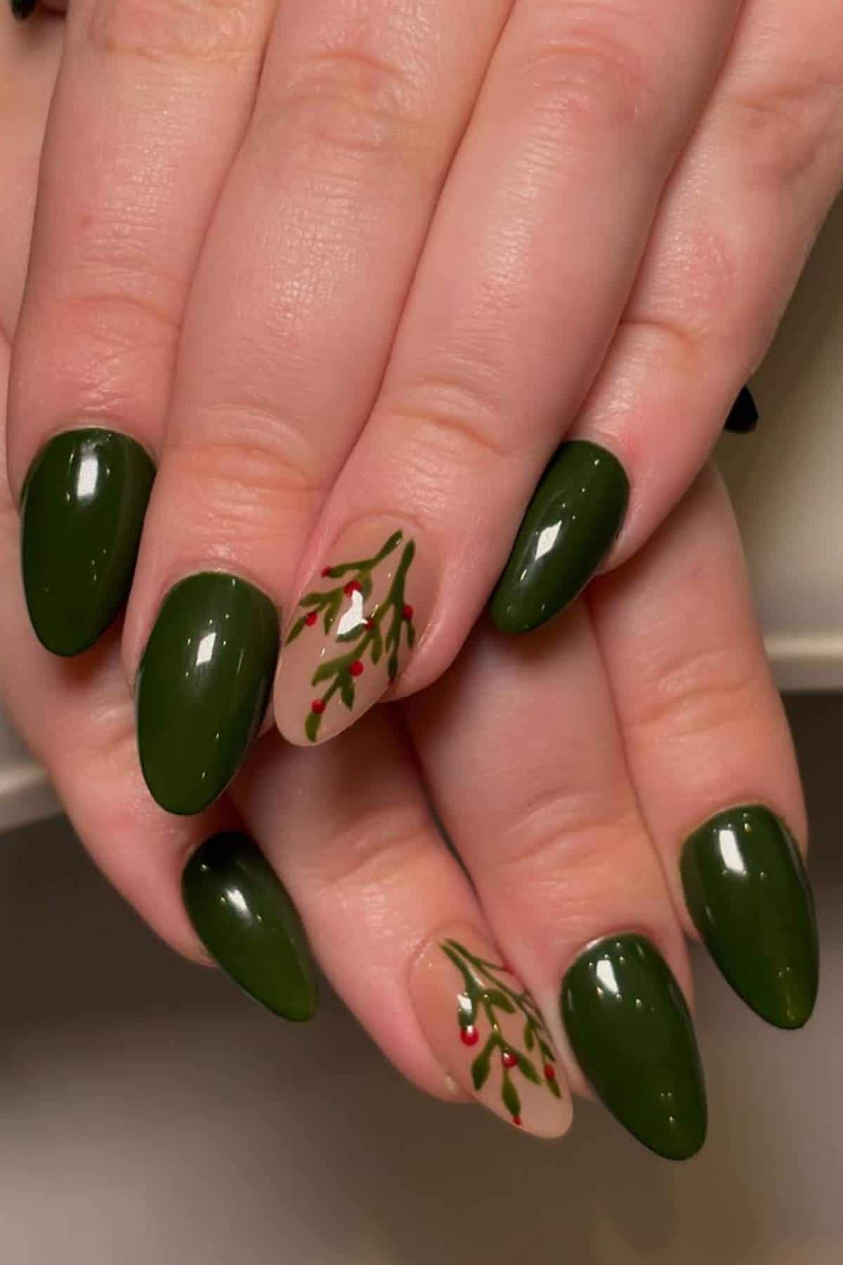 Hands with green-painted nails; two nails feature a nude base with green and red branch-like designs, resembling a festive or botanical theme.