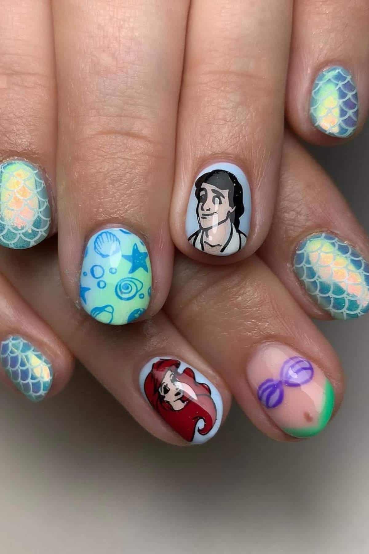Fingernails with colorful nail art featuring mermaid scales, seashells, and cartoon characters resembling Ariel and Prince Eric from "The Little Mermaid.