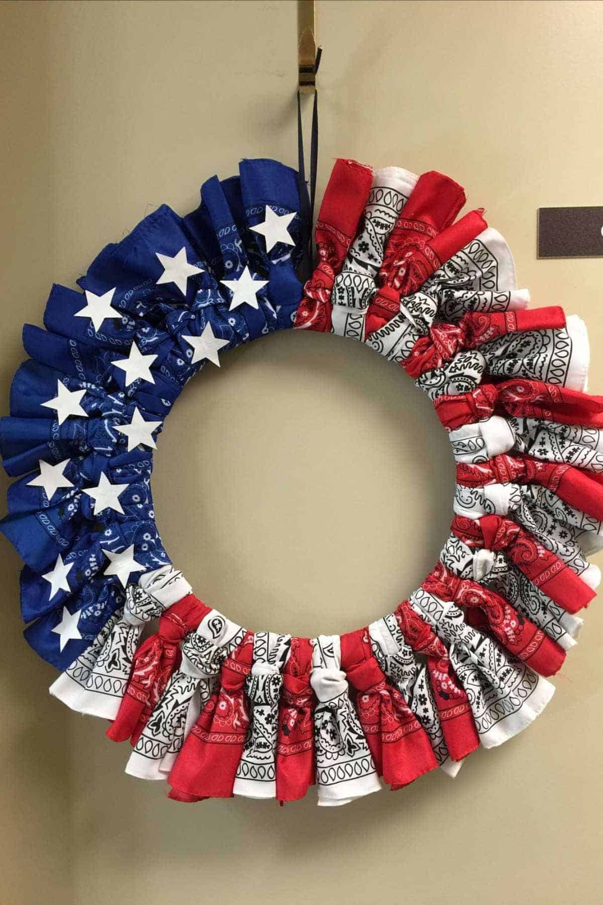 A wreath made of blue, red, and white bandanas arranged in a patriotic pattern with white stars on the blue section, resembling the American flag.