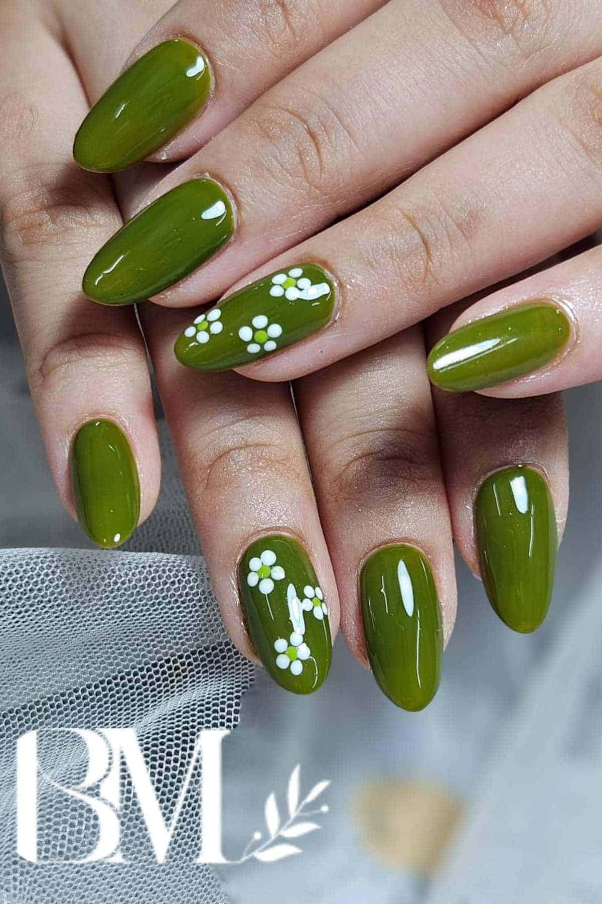Hands with almond-shaped, olive green nails; some nails feature small white daisy designs.