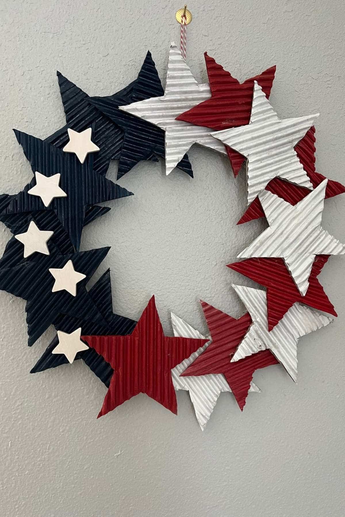A wreath made of corrugated stars in red, white, and blue colors hangs on a wall, arranged in a circular pattern.