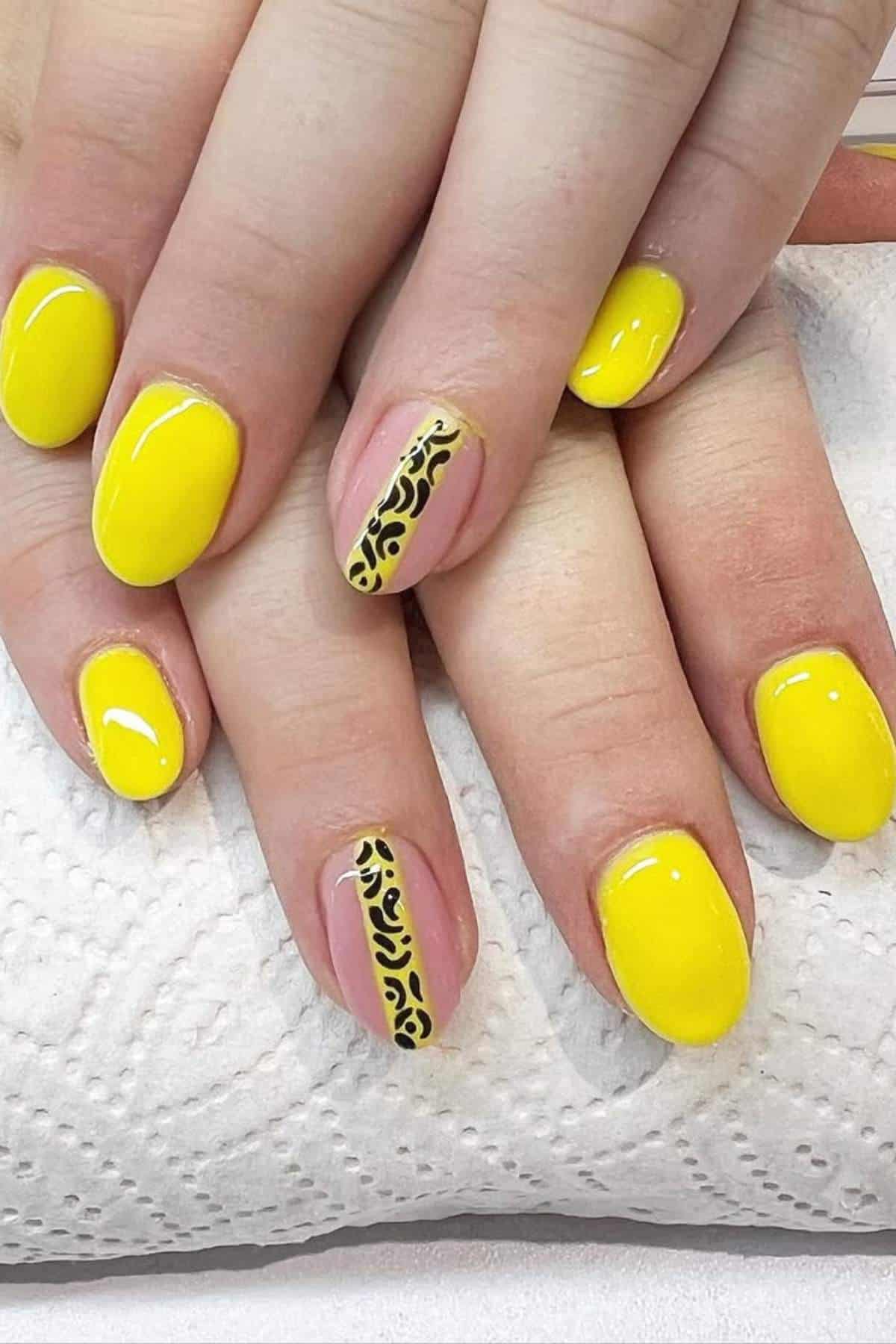 Hands with bright yellow manicured nails; one accent nail on each hand features a nude base with black and yellow abstract swirl design.
