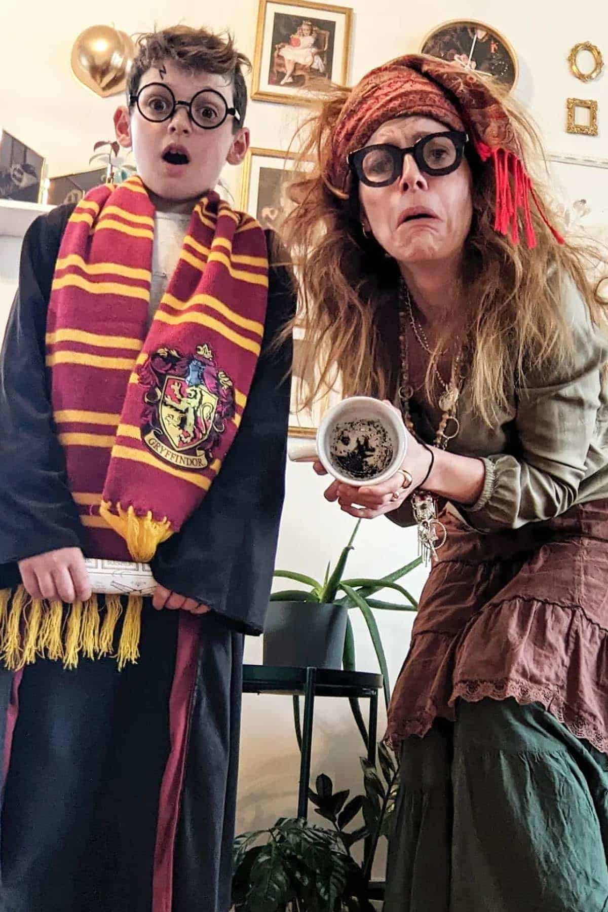 A child dressed as Harry Potter and an adult dressed as Professor Trelawney stand indoors; the adult holds a teacup and both have surprised expressions.