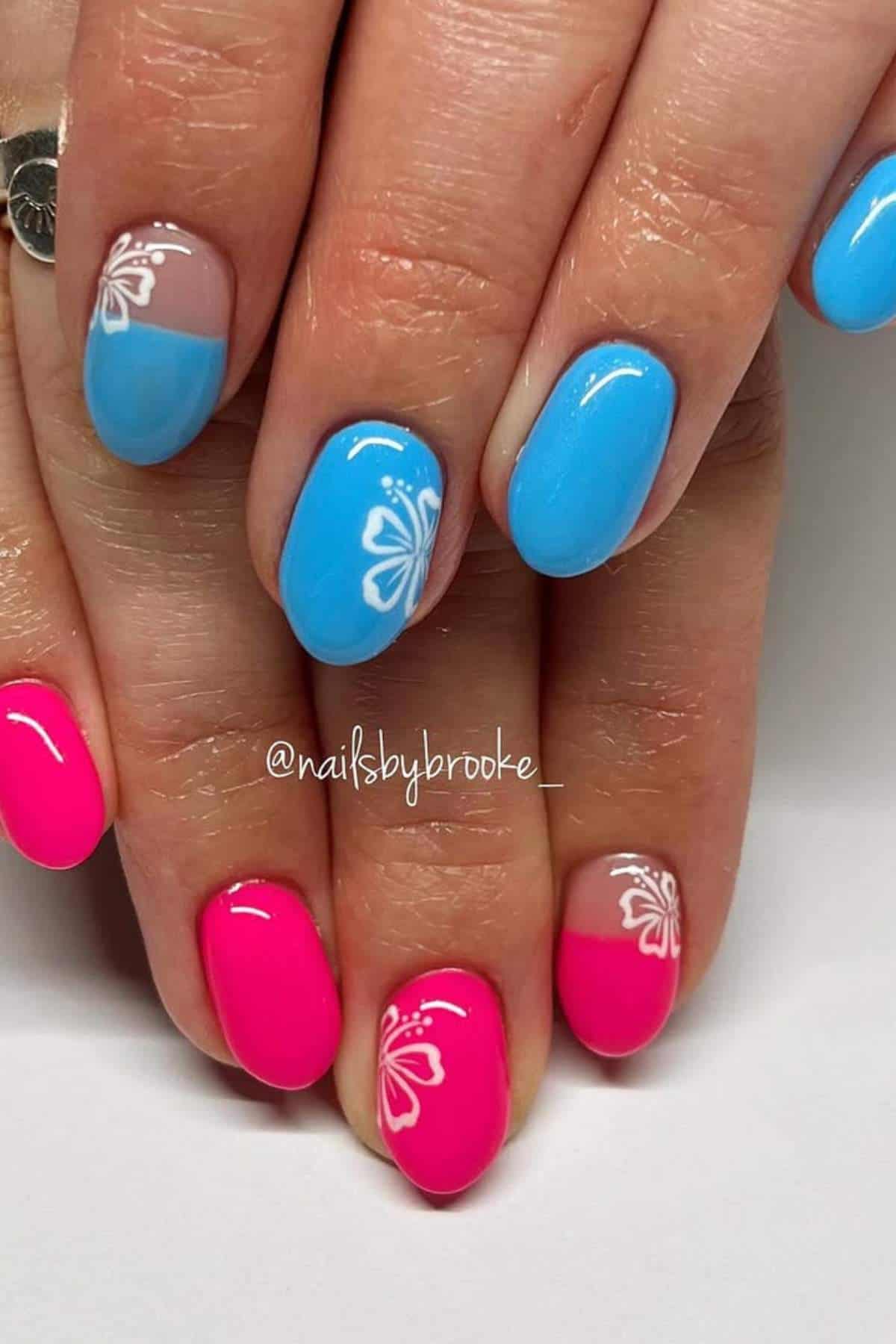 Hands with fingernails painted in bright blue and pink polish, some nails featuring white butterfly designs near the cuticles.