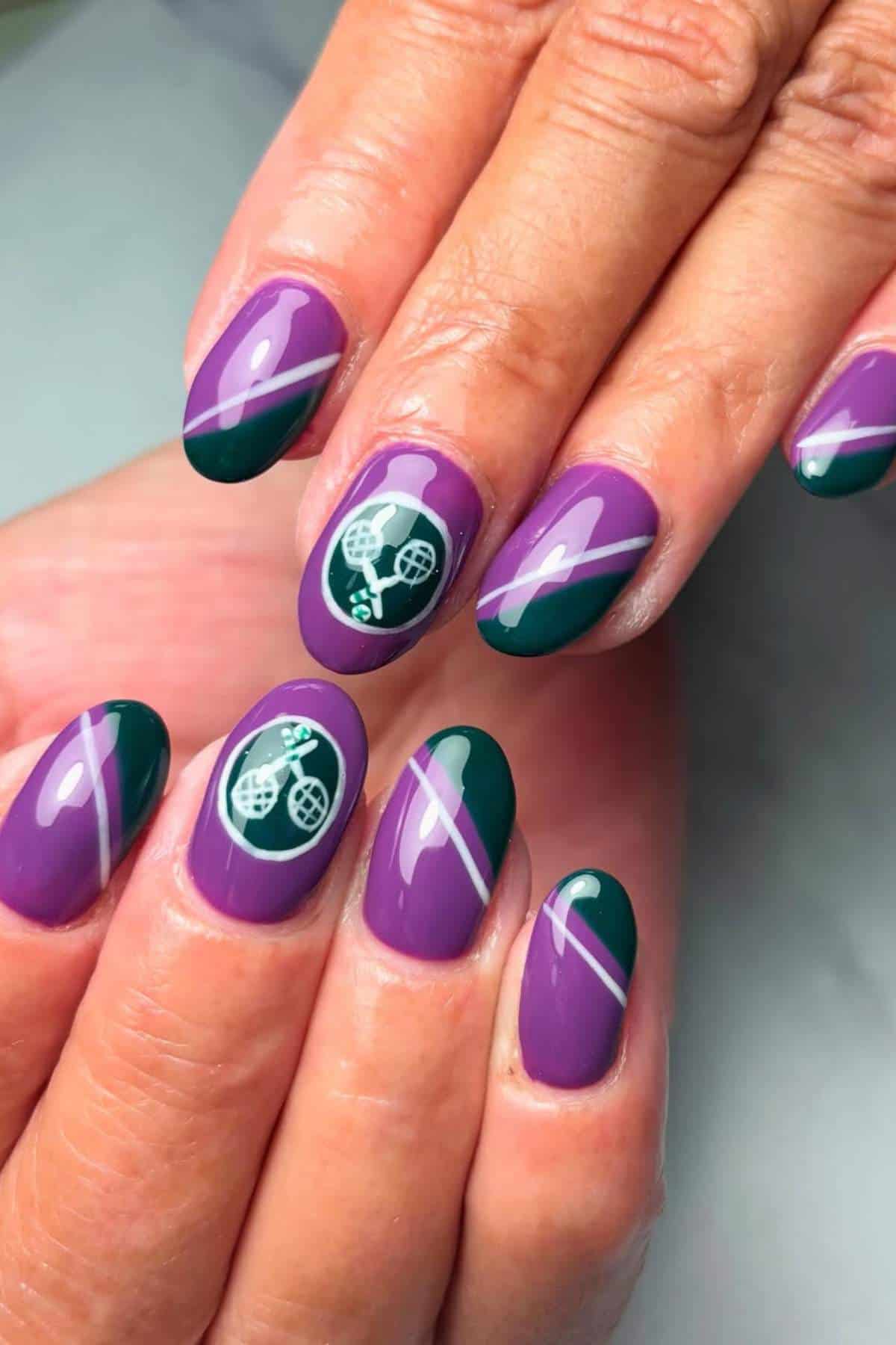 Close-up of hands with purple and green manicured nails, featuring diagonal stripes and tennis-themed designs on two fingernails.