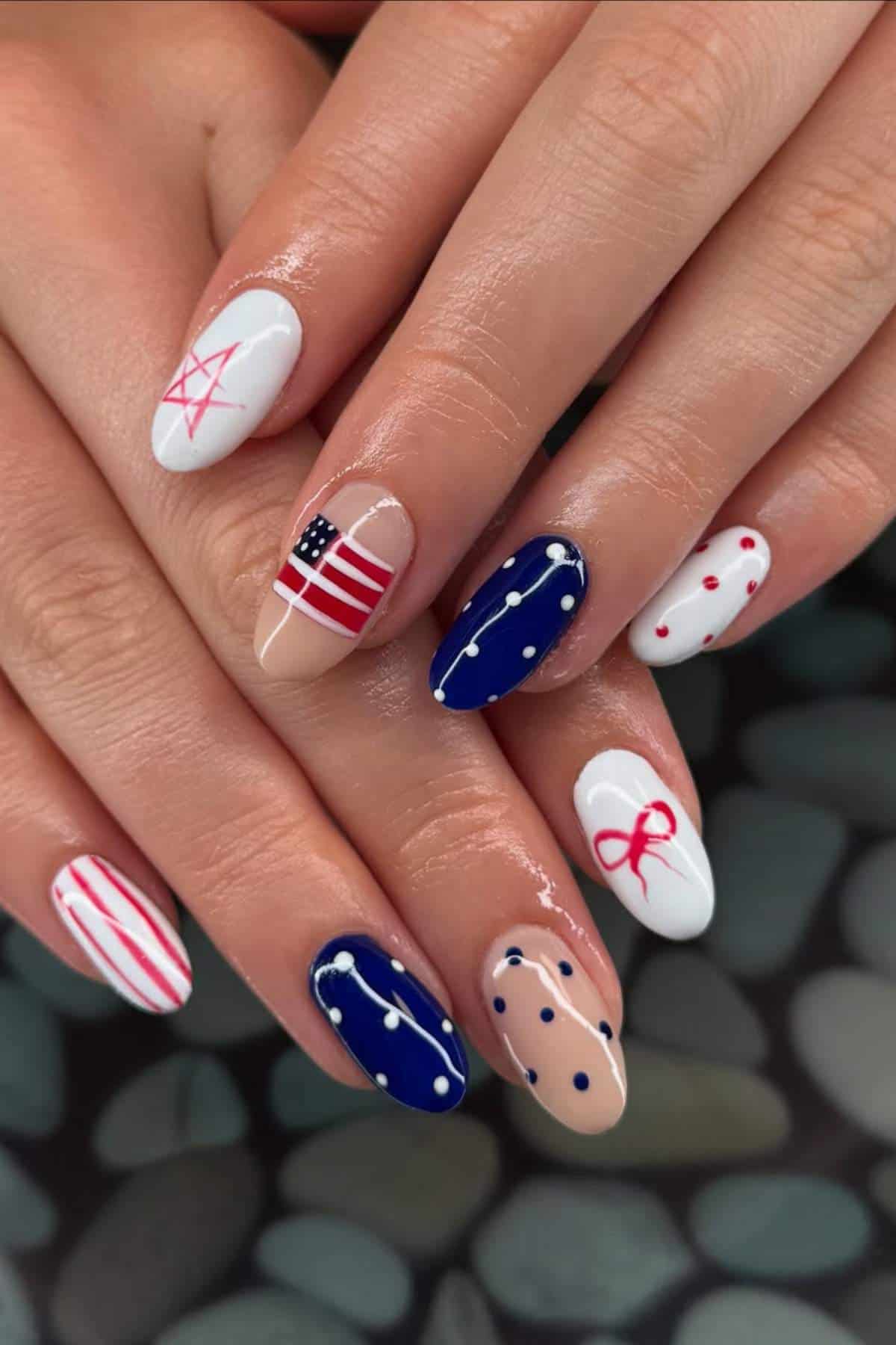 Hands with manicured nails featuring patriotic designs, including stars, stripes, dots, an American flag, and red, white, and blue colors.