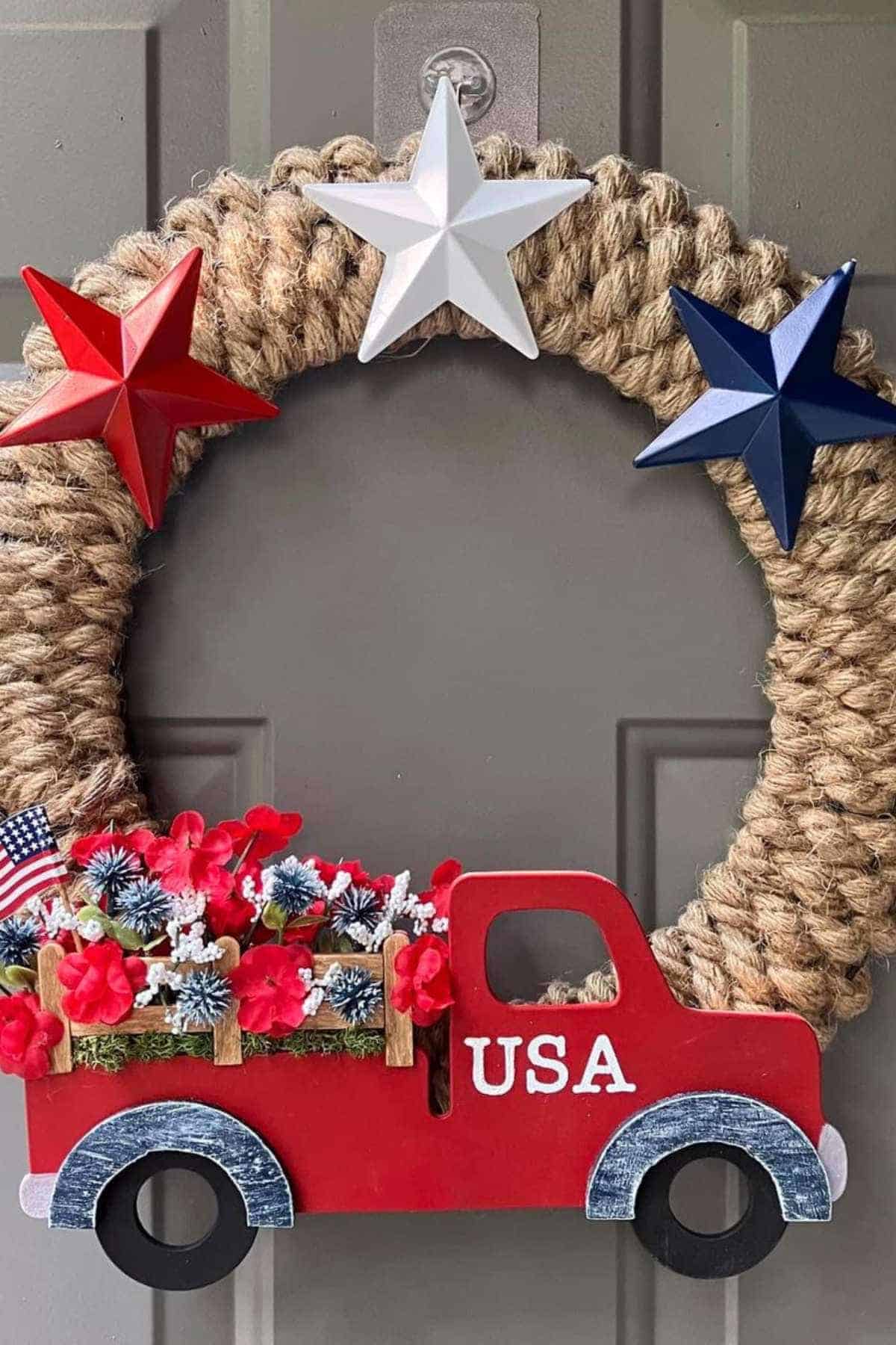 A wreath made of rope decorated with red, white, and blue stars, and a red truck cutout carrying flowers and mini American flags, labeled "USA.