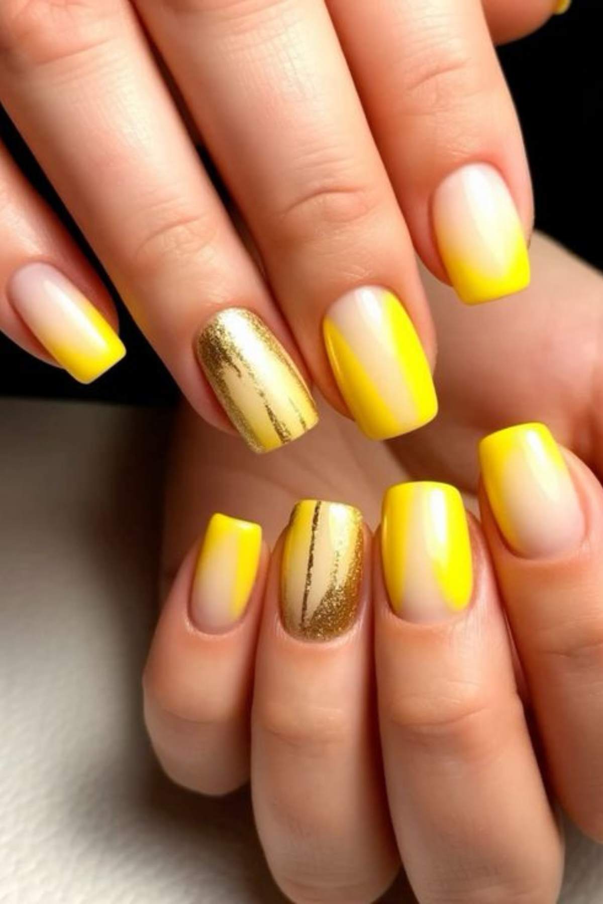 Hands with square-shaped nails featuring yellow ombre, solid yellow polish, and gold glitter accent designs.