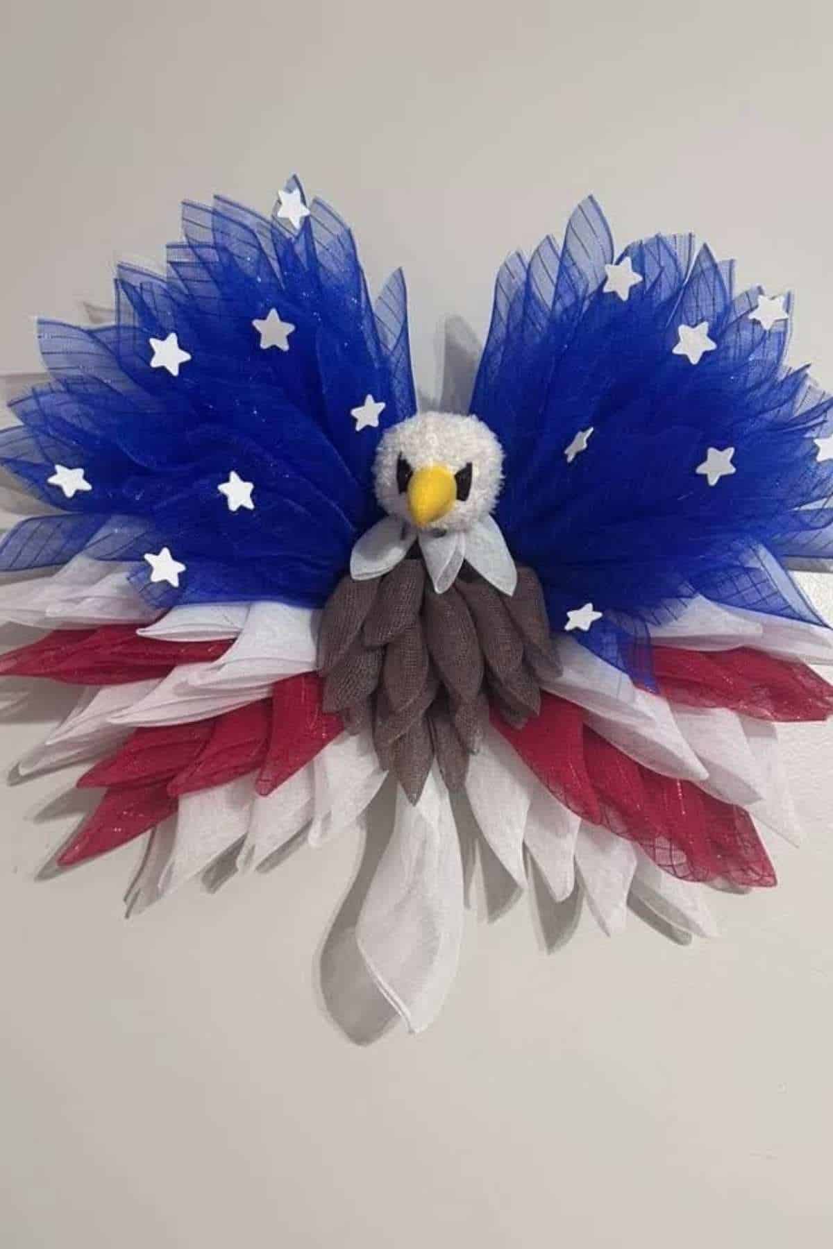 A decorative eagle made of red, white, and blue tulle with star accents is mounted on a wall, resembling the American flag.